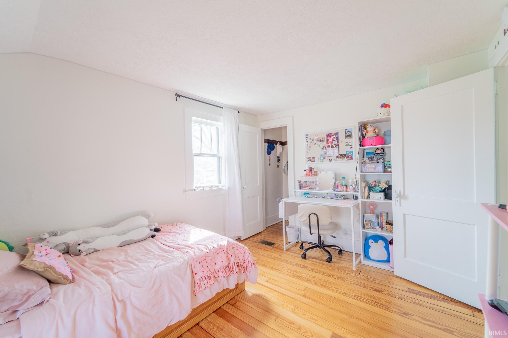 Bedroom featuring light wood finished floors and vaulted ceiling