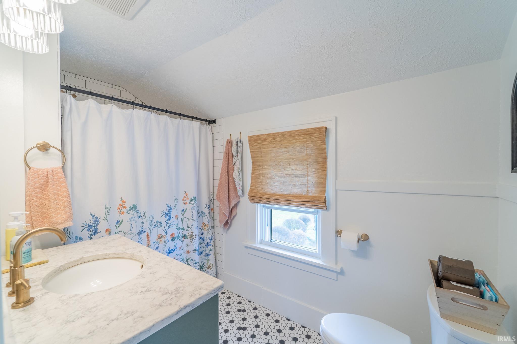 Full bathroom with a shower with shower curtain, vanity, and vaulted ceiling