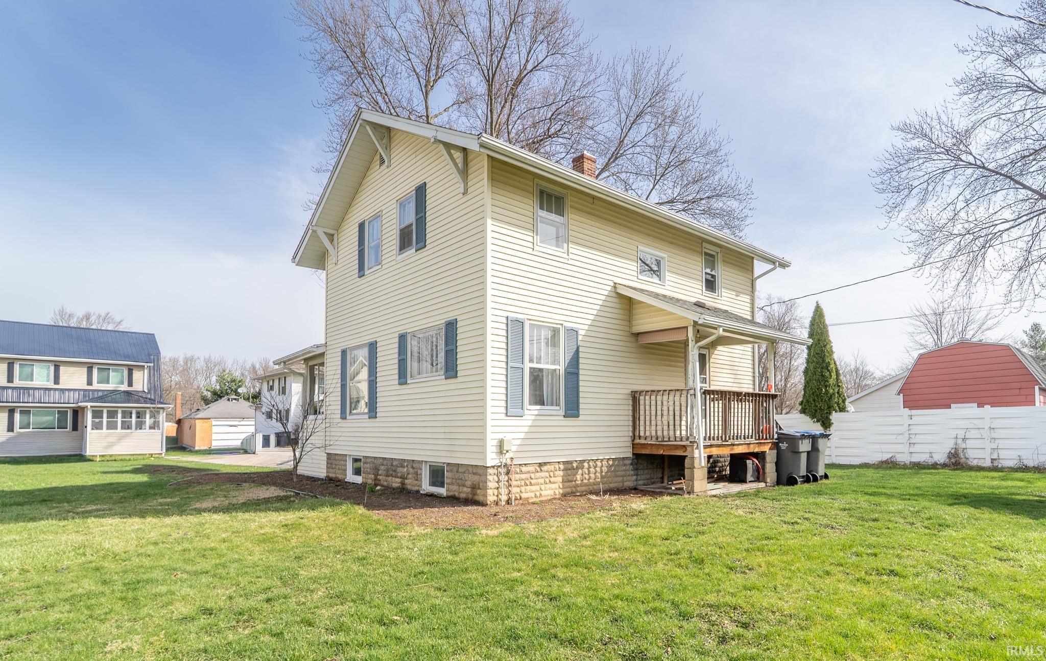 Back of house with a lawn, a chimney, and a deck