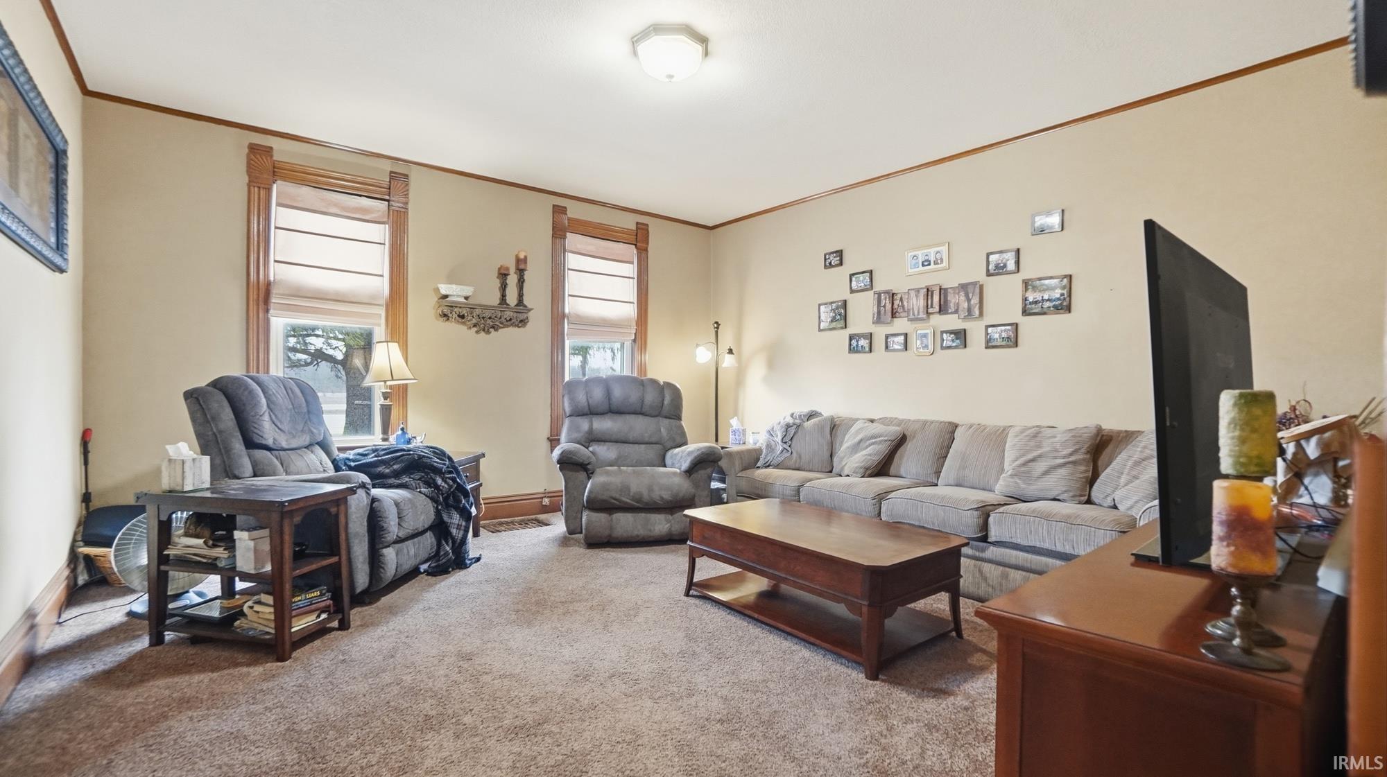 Living area with light colored carpet and ornamental molding