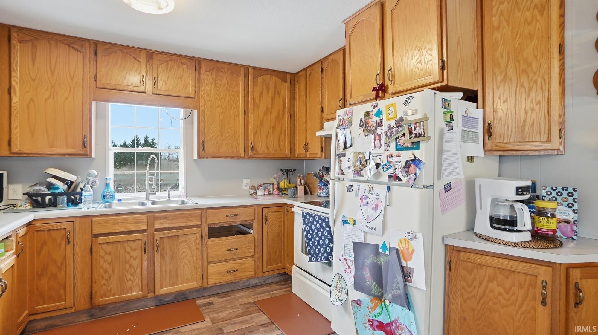 Kitchen with white appliances, light countertops, light wood-type flooring, and wood finish cabinets