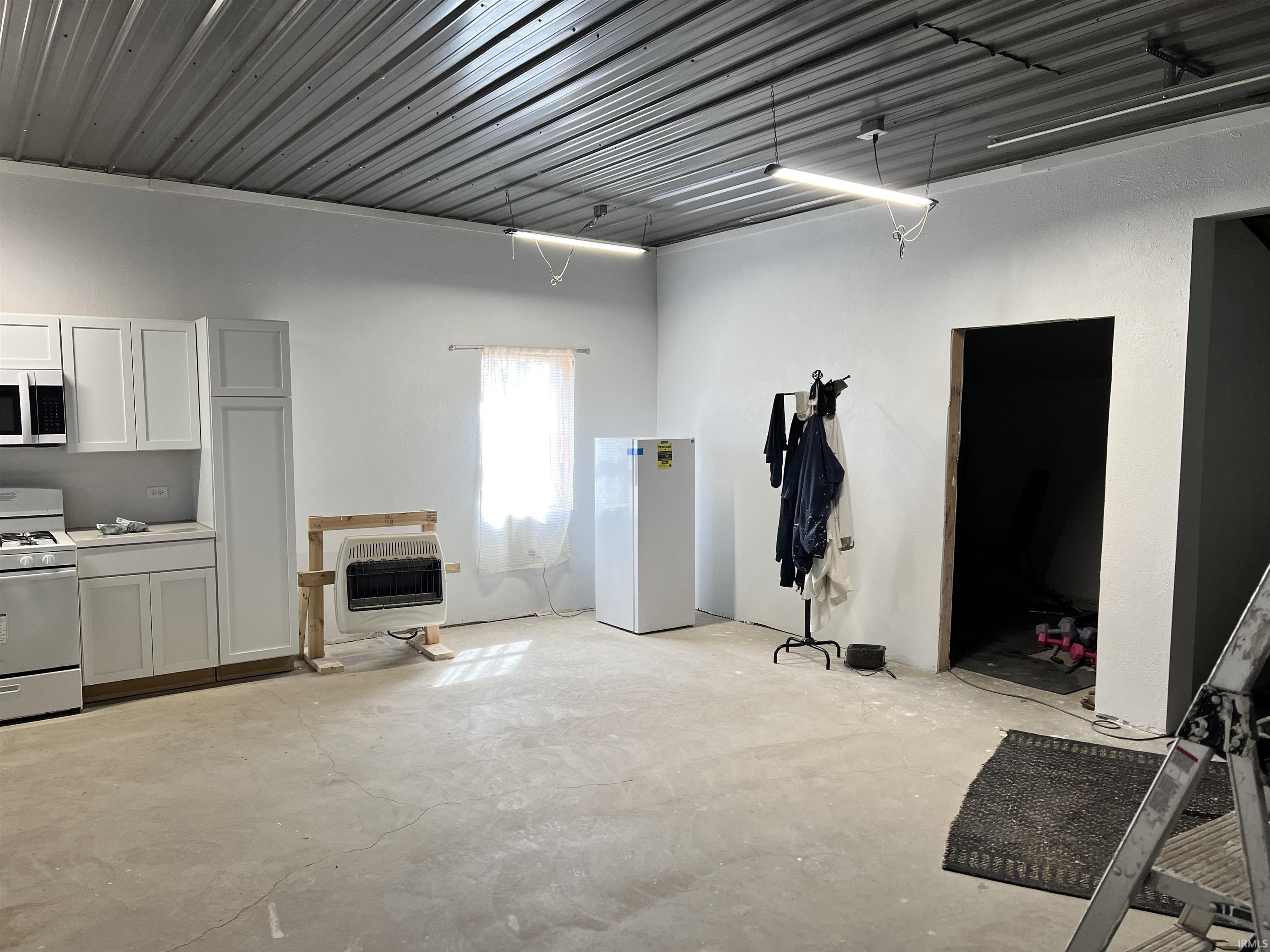 Unfurnished living room with unfinished concrete floors and heating unit