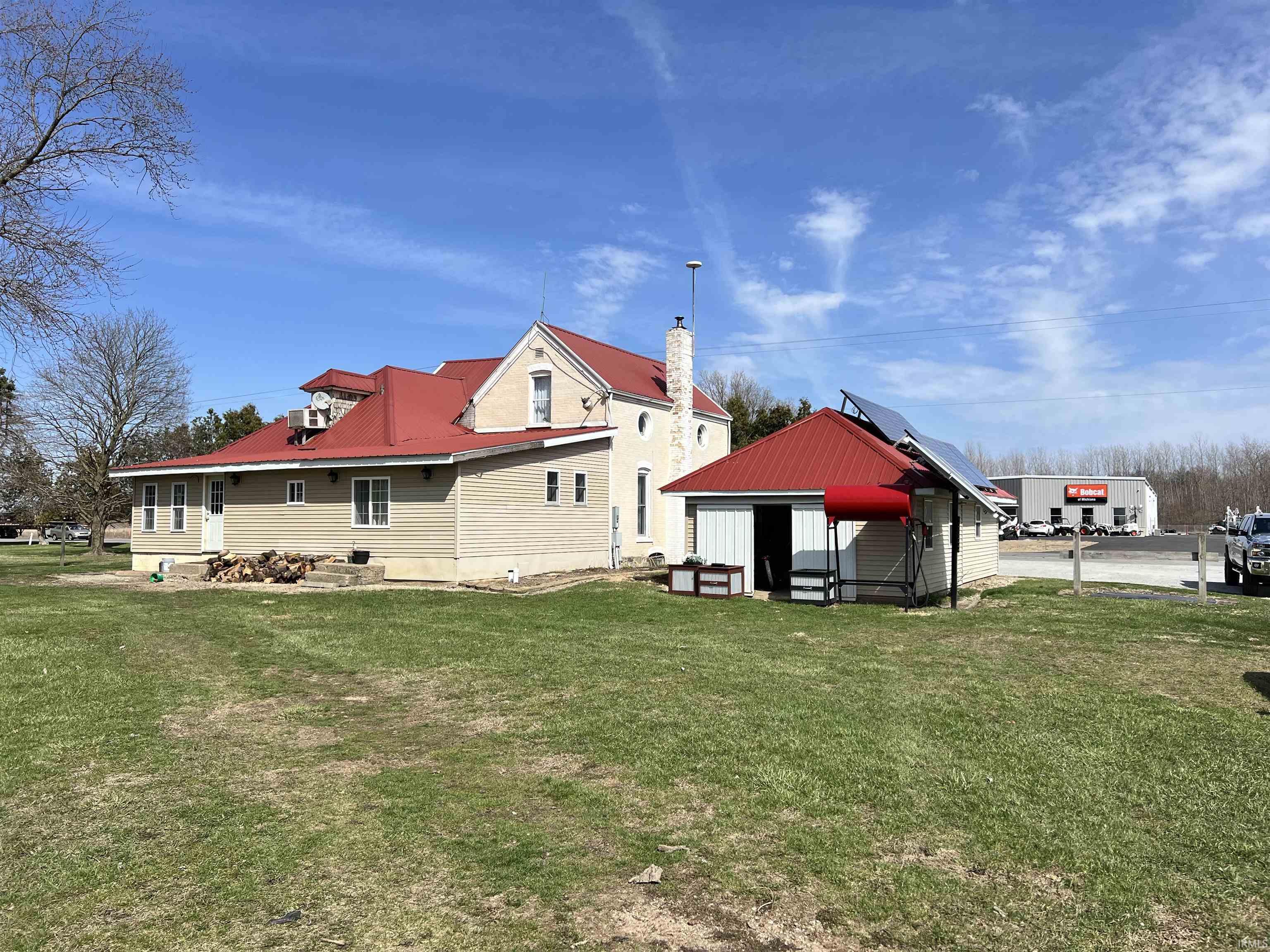 Back of property with a lawn, a metal roof, and a chimney