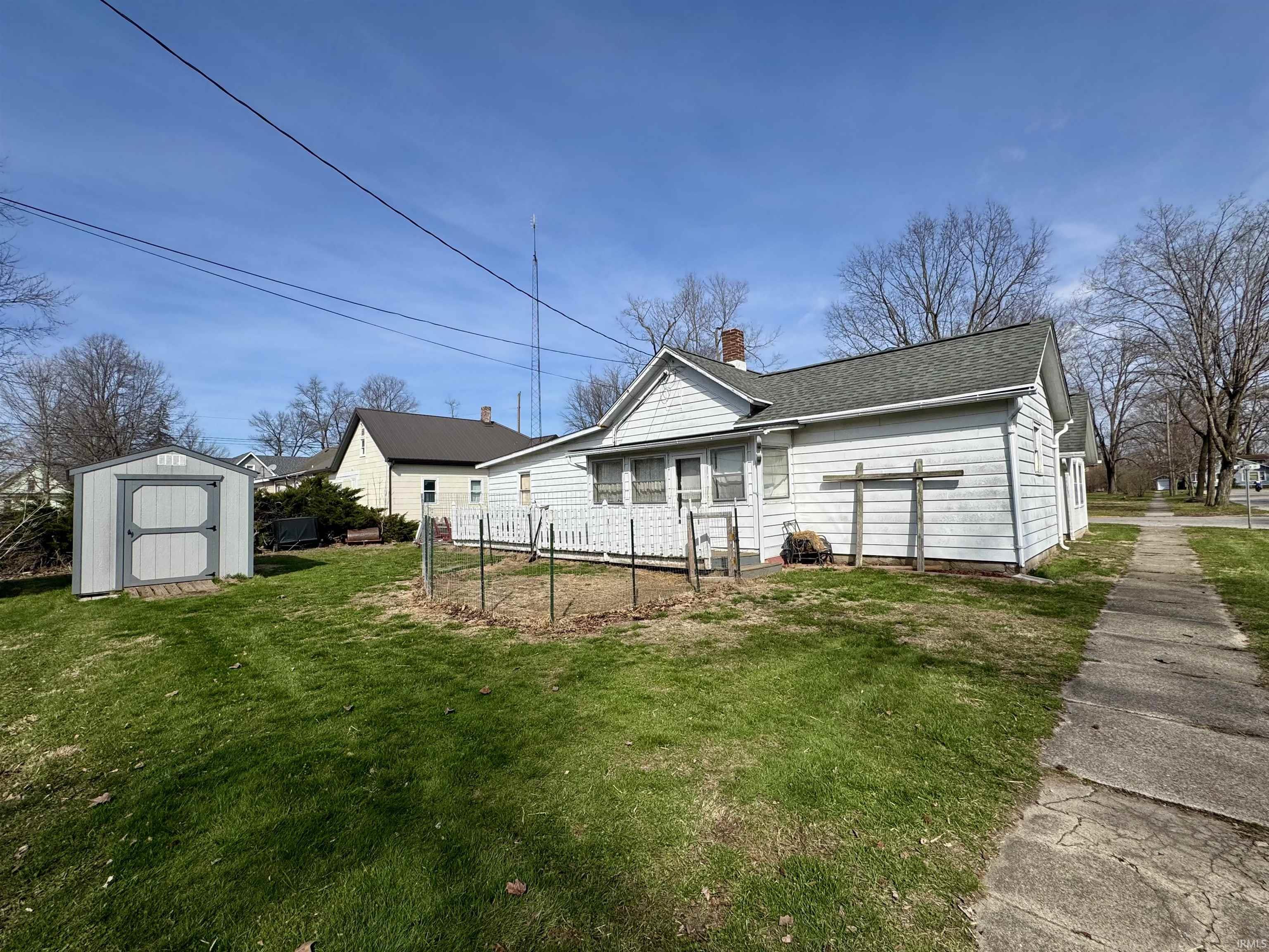 Back of property with a storage shed, a chimney, and roof with shingles