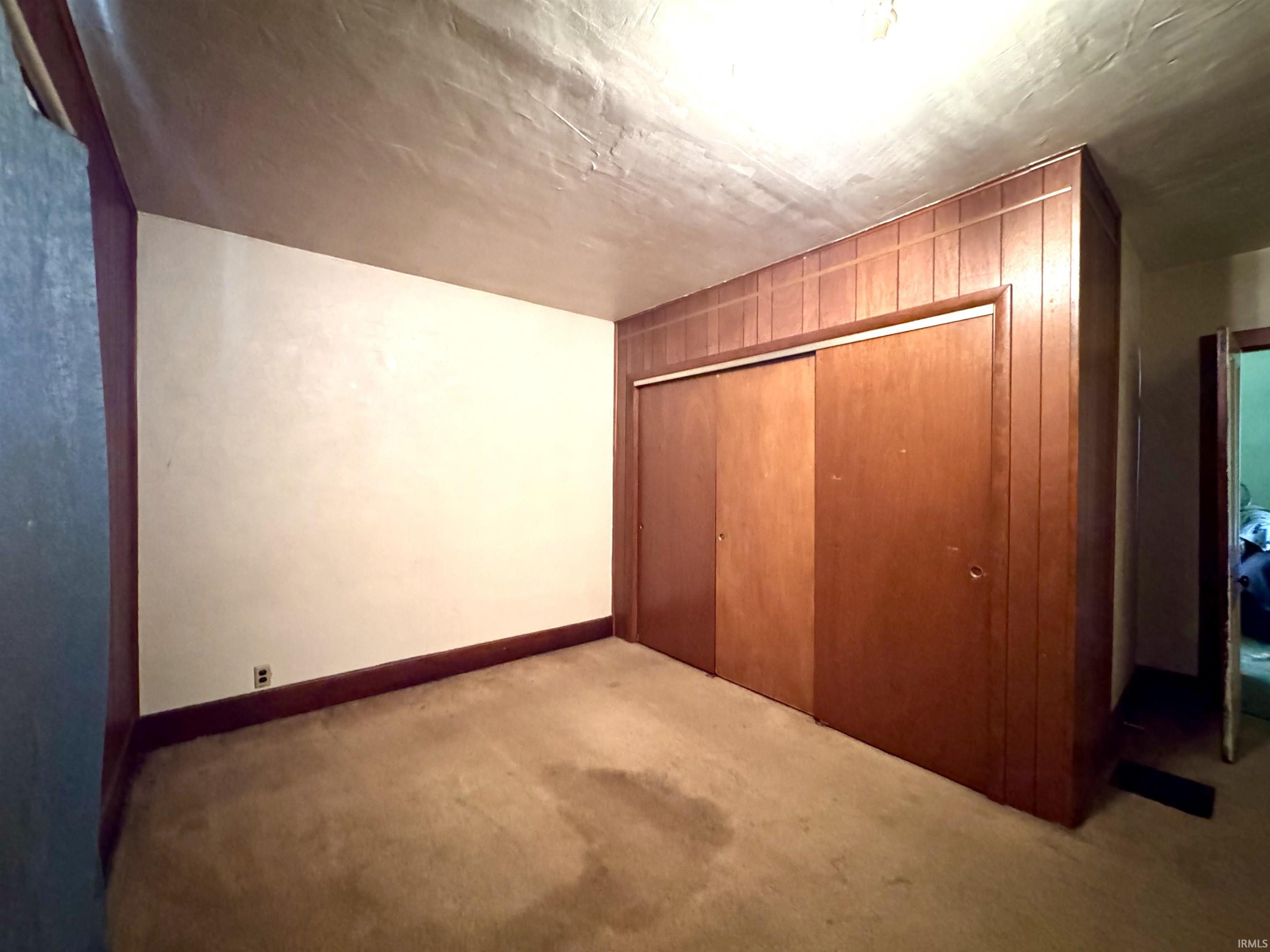 Unfurnished bedroom featuring light carpet and a closet
