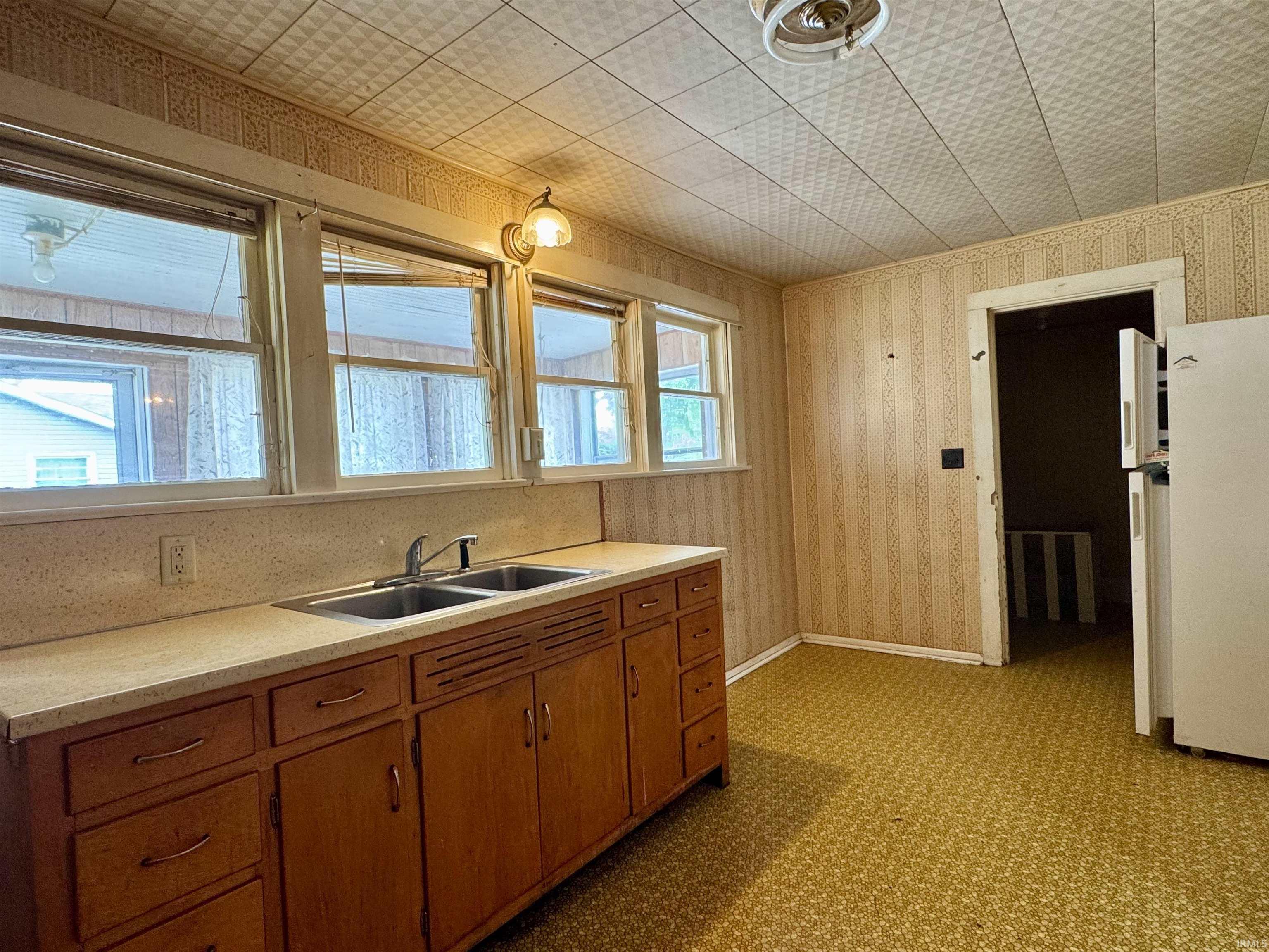 Kitchen featuring wood cabinetry, a dual basin sink, and a light-toned countertop