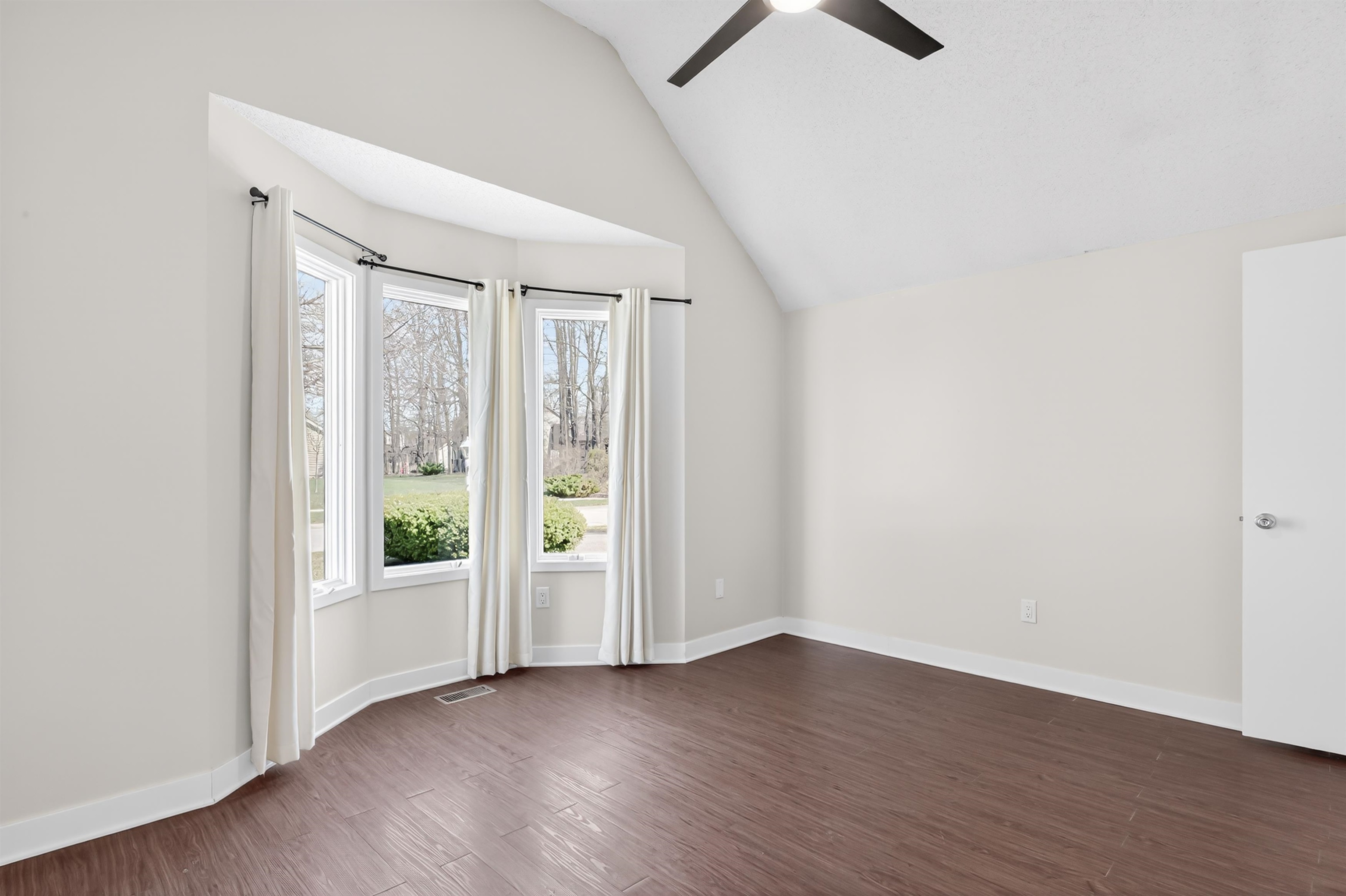 Spare room with vaulted ceiling, dark wood-style floors, and a ceiling fan