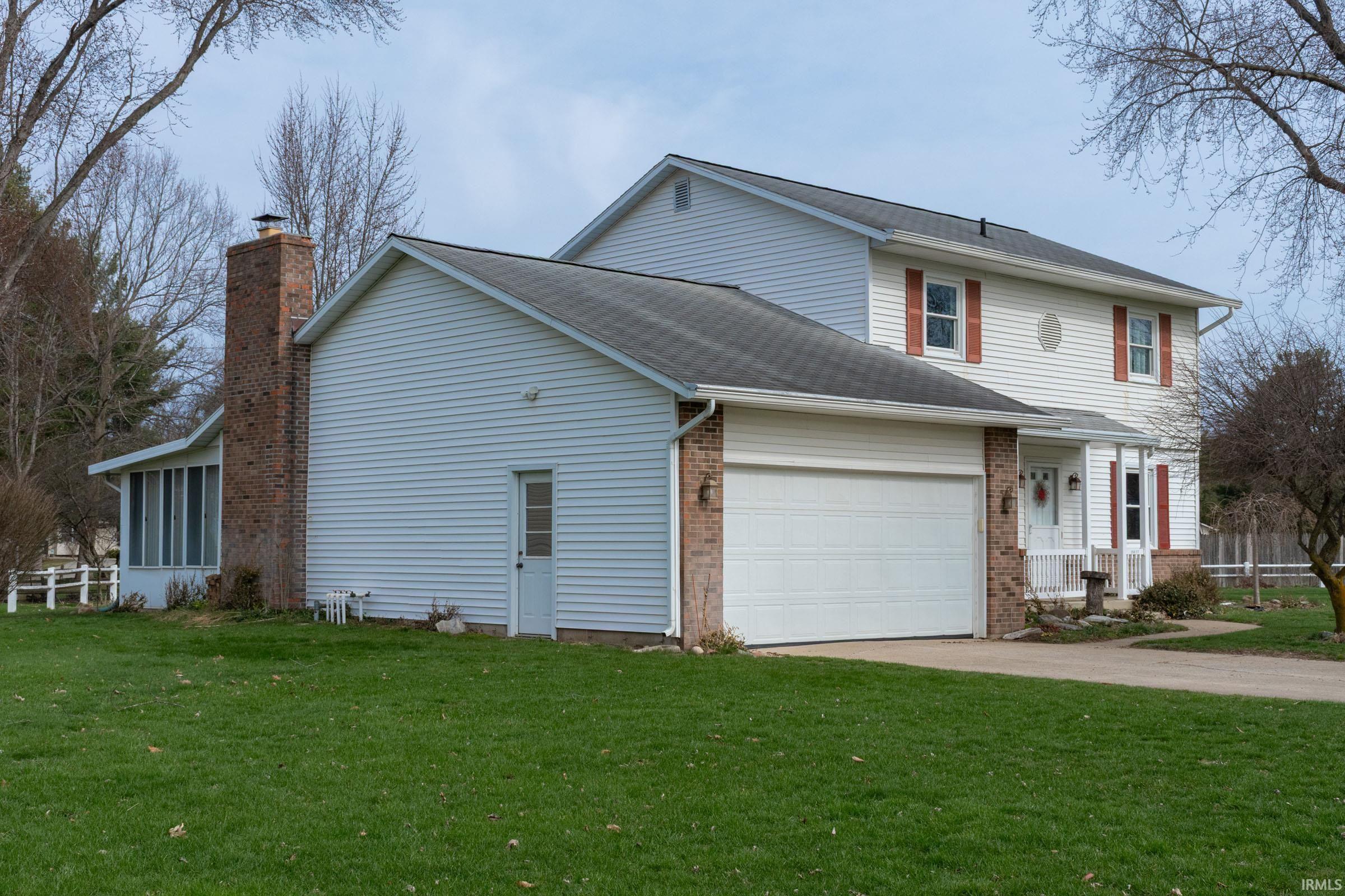 View of home's exterior featuring brick siding, concrete driveway, a garage, roof with shingles, and a chimney