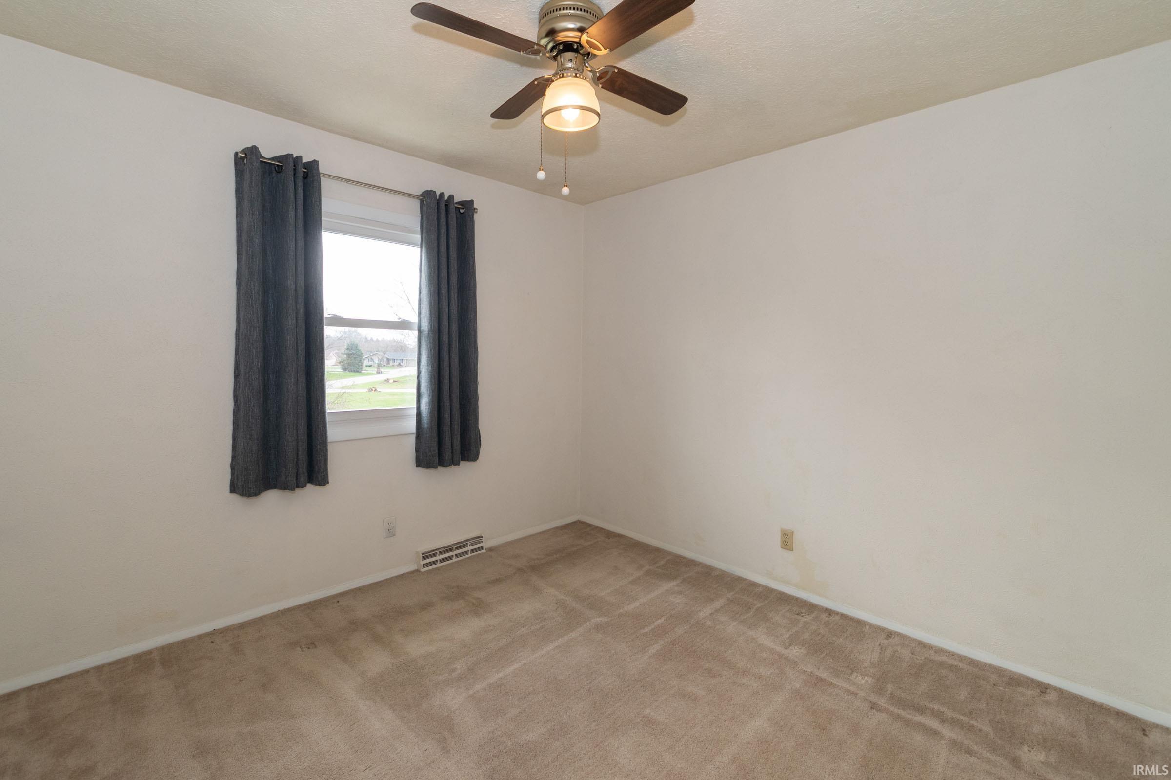 Empty room with light colored carpet and a ceiling fan