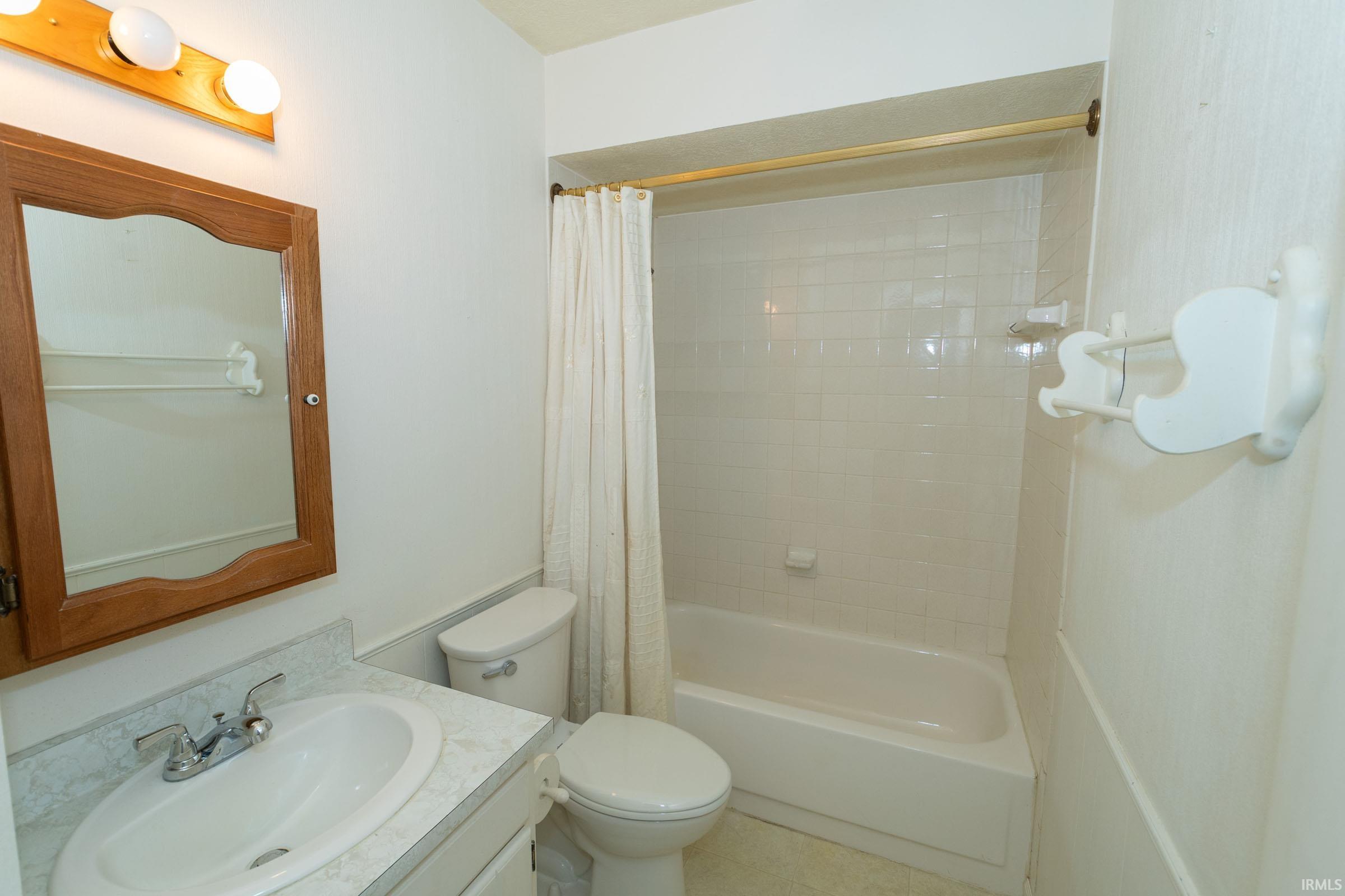 Bathroom featuring vanity and shower / bathtub combination with curtain