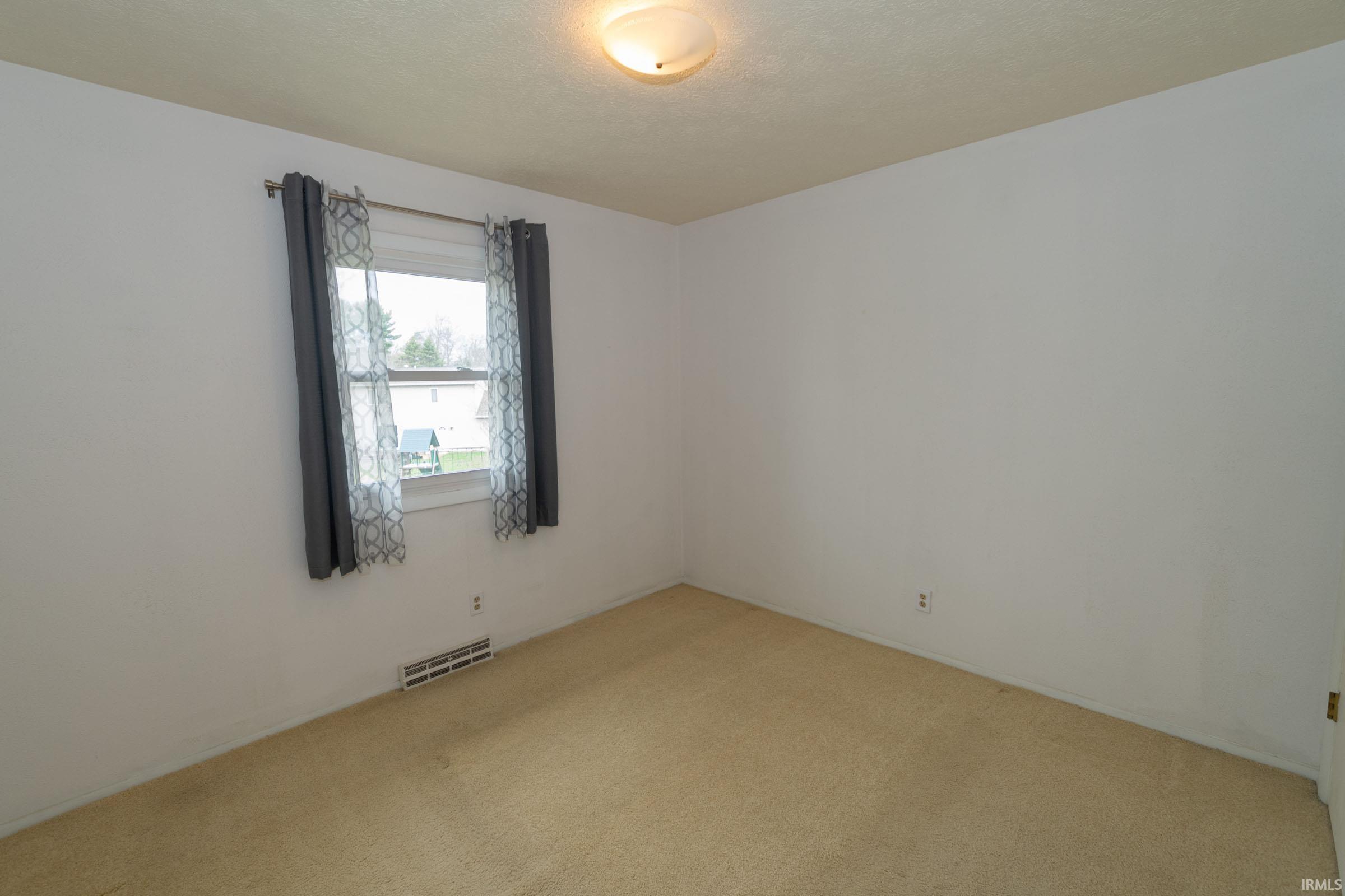 Unfurnished room with light carpet and a textured ceiling
