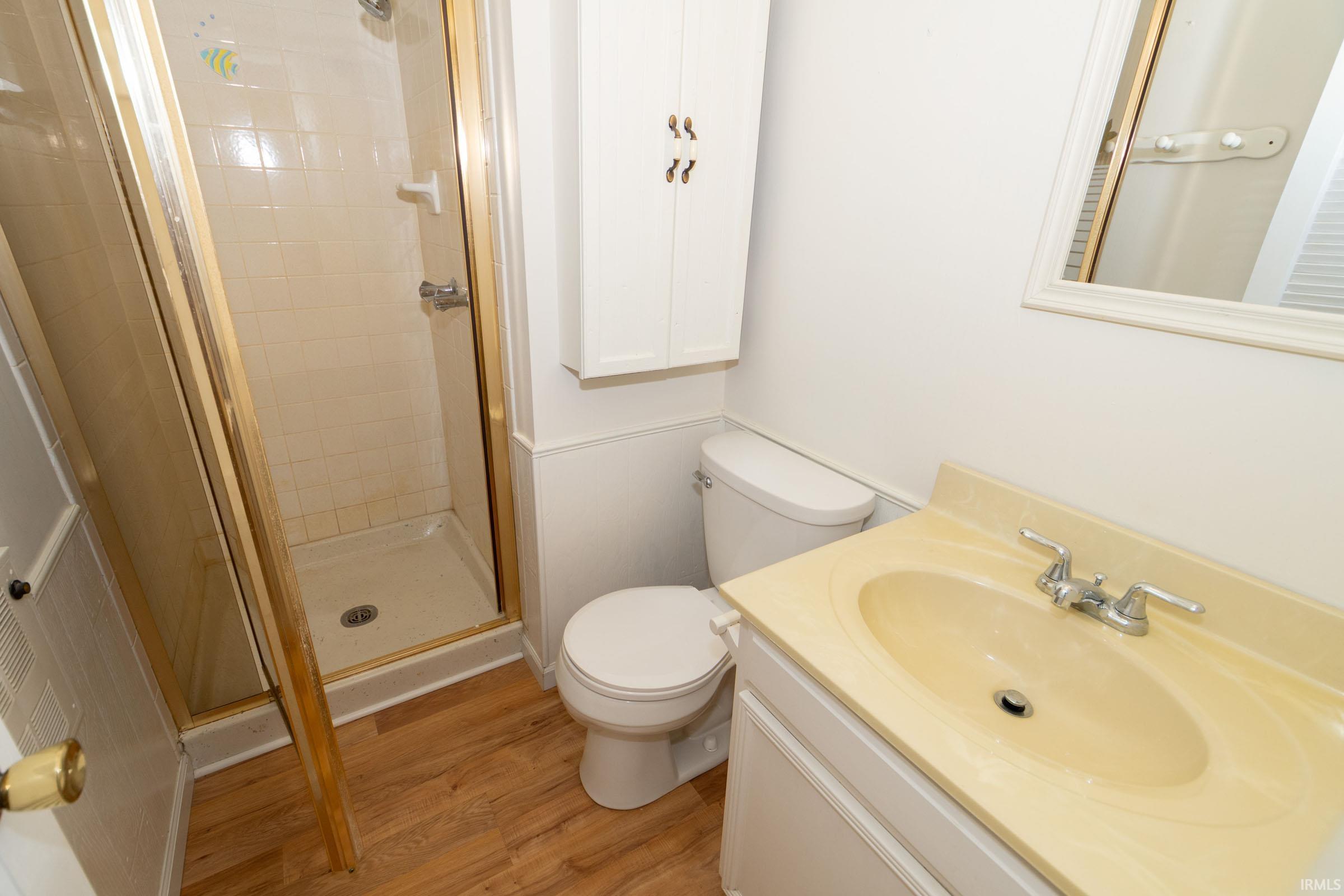 Full bath featuring vanity, light wood finished floors, and a stall shower