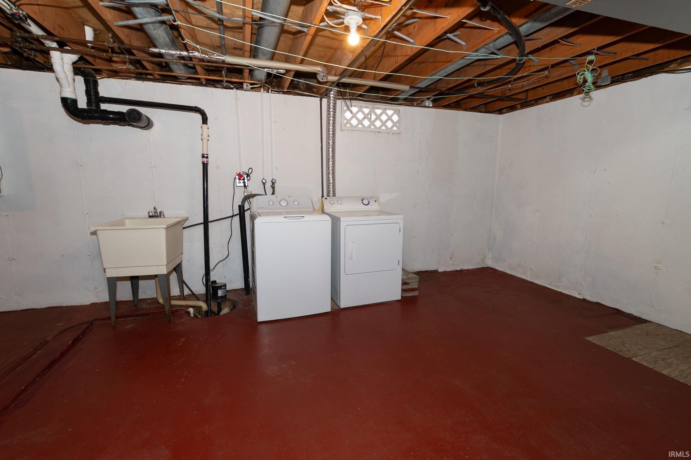 Unfinished below grade area featuring washing machine and dryer and a sink