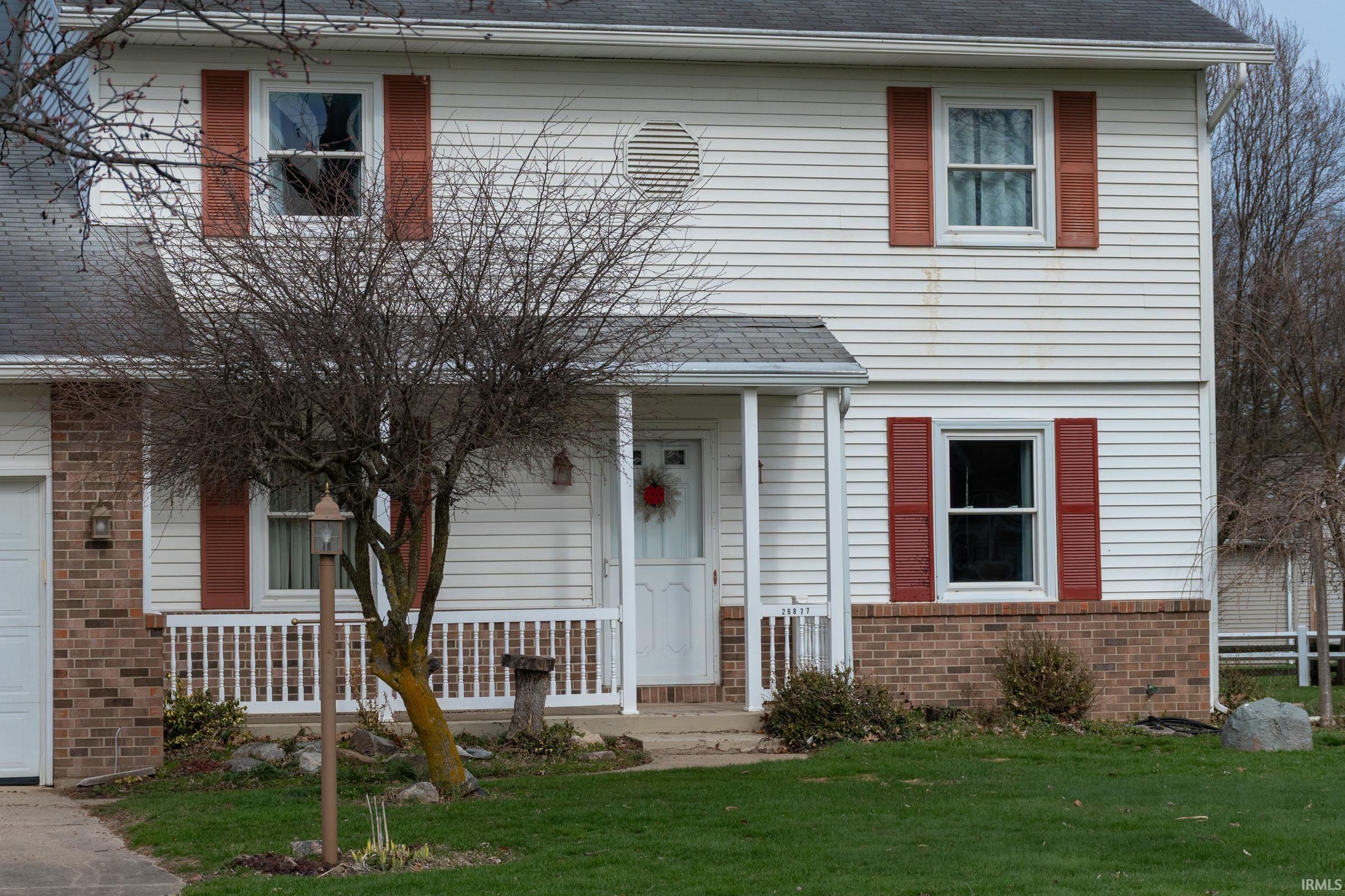View of front of house with roof with shingles, brick siding, and a front lawn