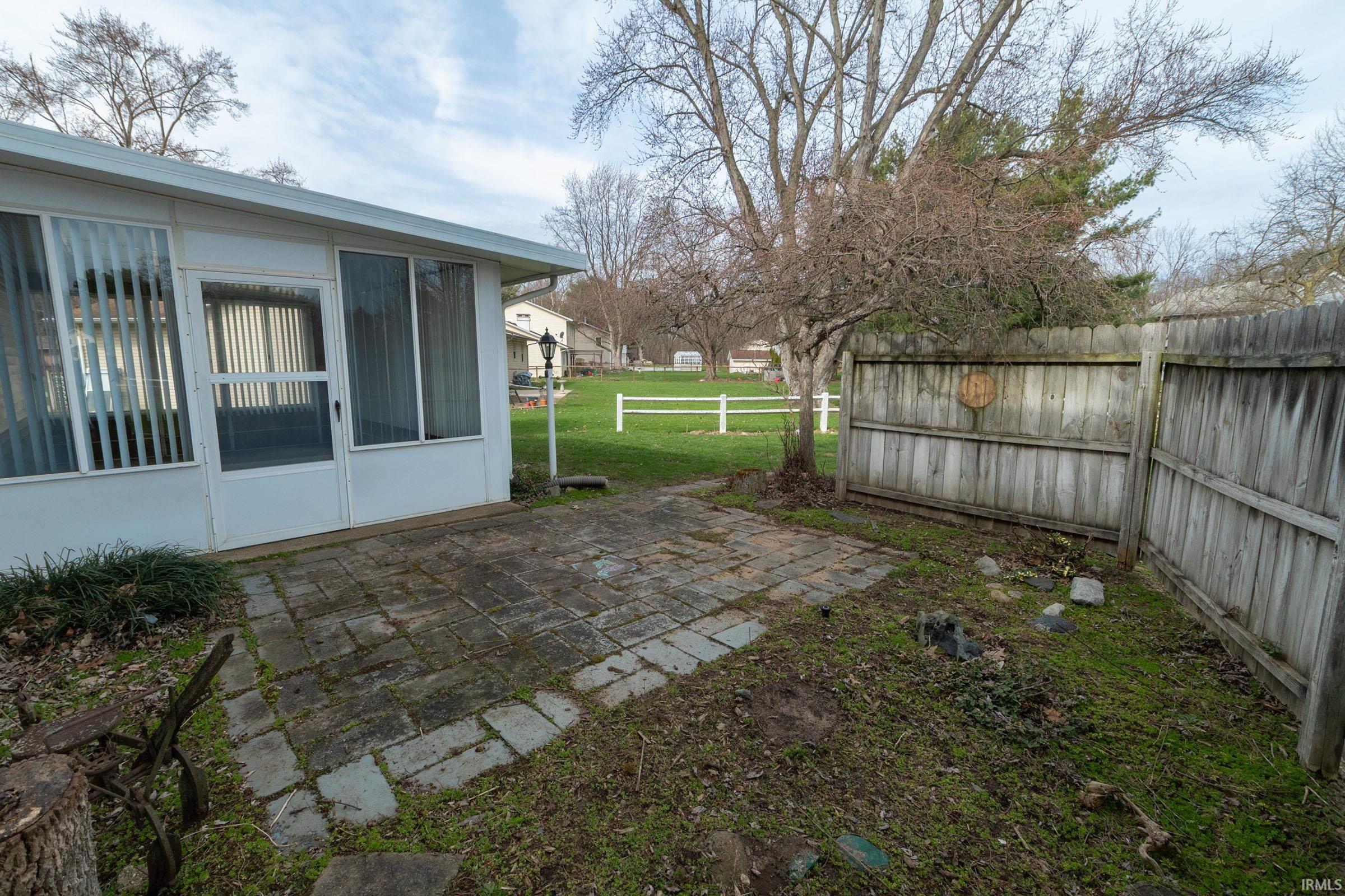Fenced backyard featuring a patio area and a sunroom