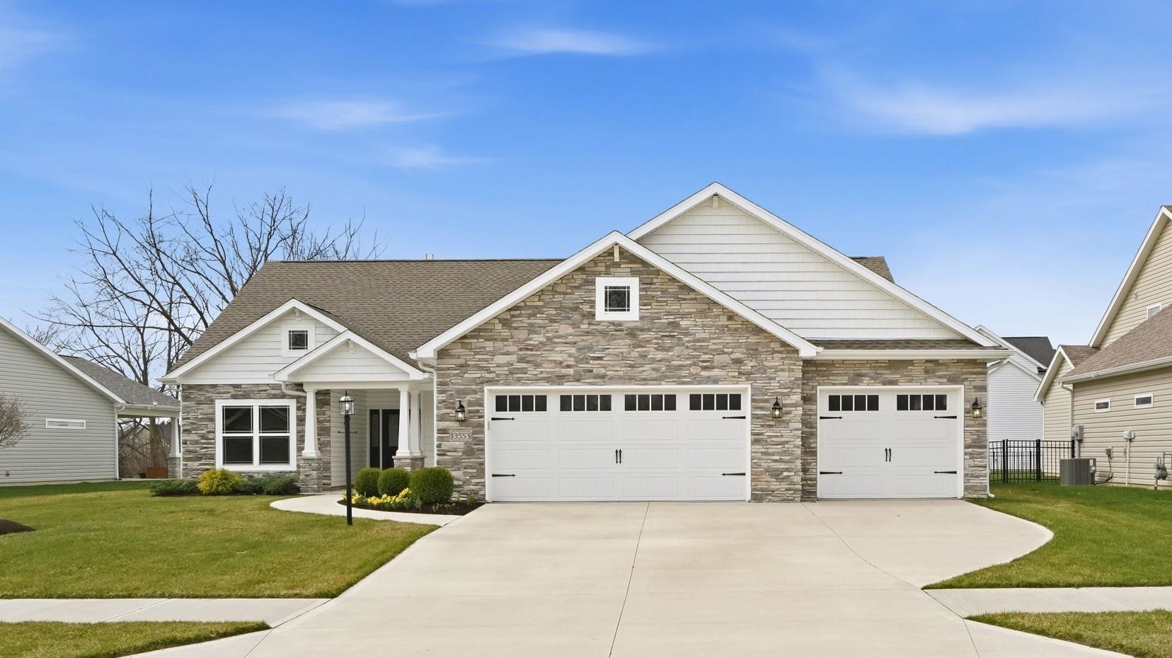Craftsman inspired home featuring a front yard, driveway, stone siding, and a garage
