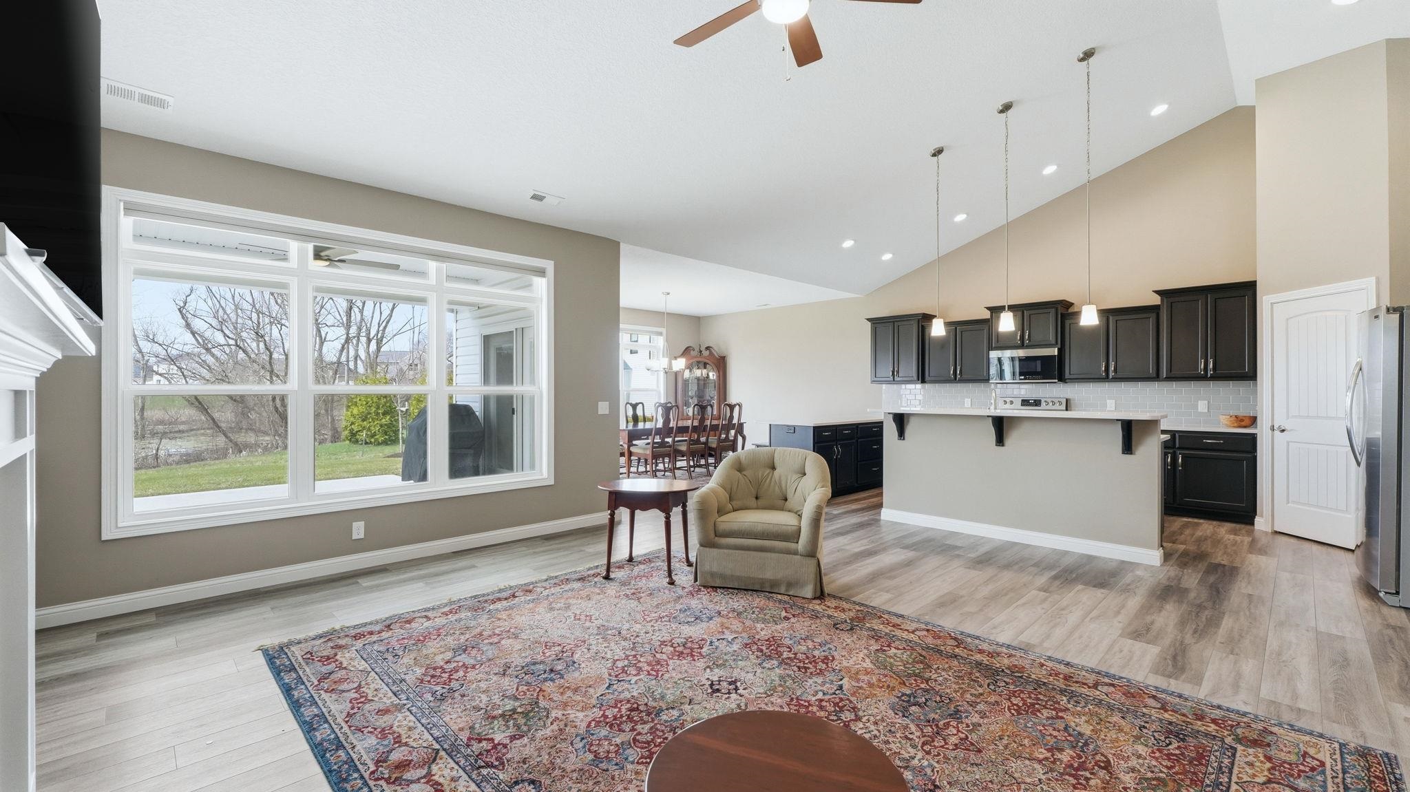 Living room with a ceiling fan, lofted ceiling, light wood-style flooring, and recessed lighting