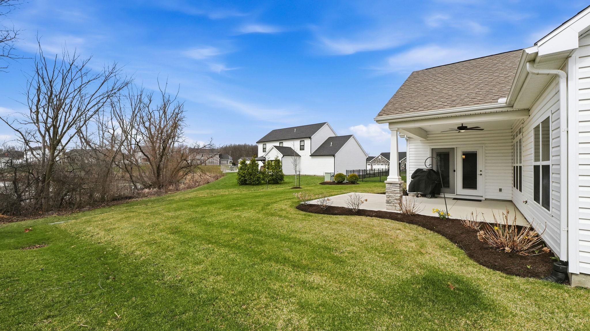 View of green lawn with ceiling fan and a patio area