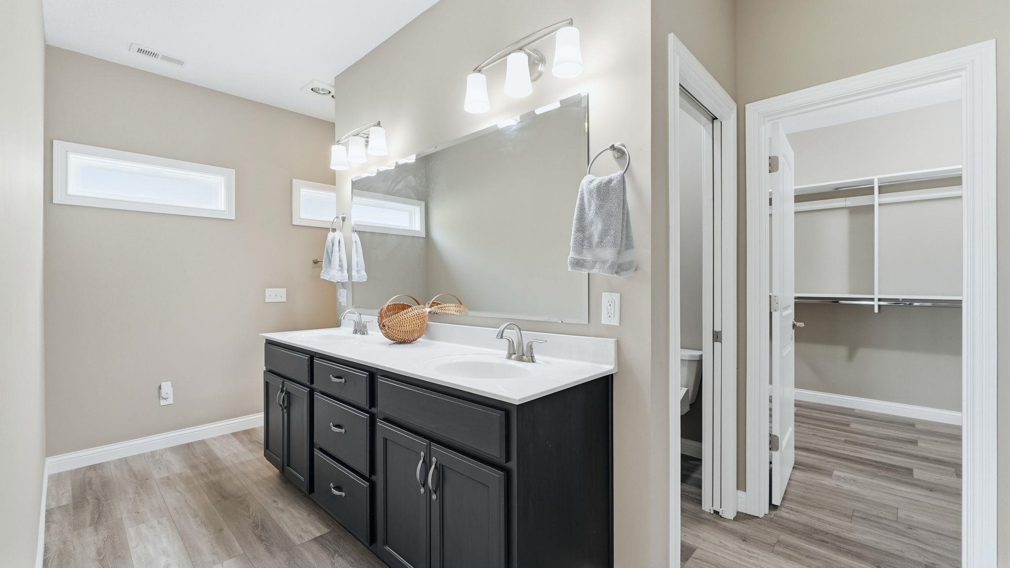 Primary Bedroom's Full bath with double vanity, light wood-style flooring, and a spacious closet