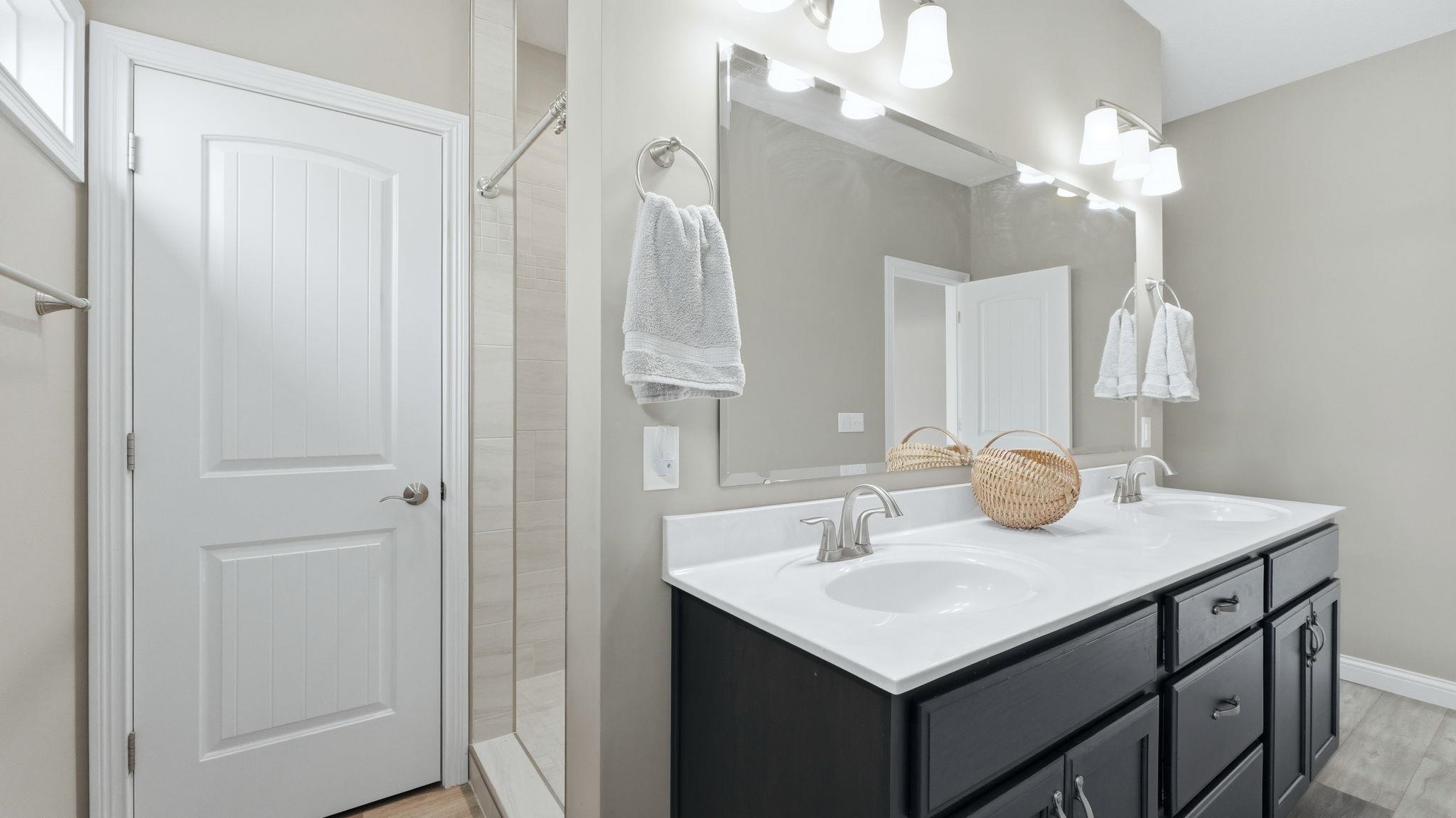 Primary Bedroom's Full bathroom featuring double vanity, a walk in shower, and light wood-style flooring