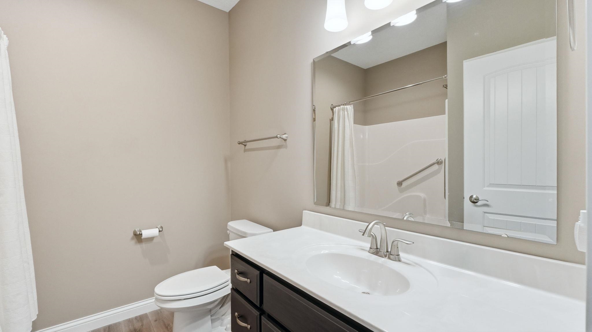 Full bathroom featuring vanity, a shower with curtain, and light wood-style floors