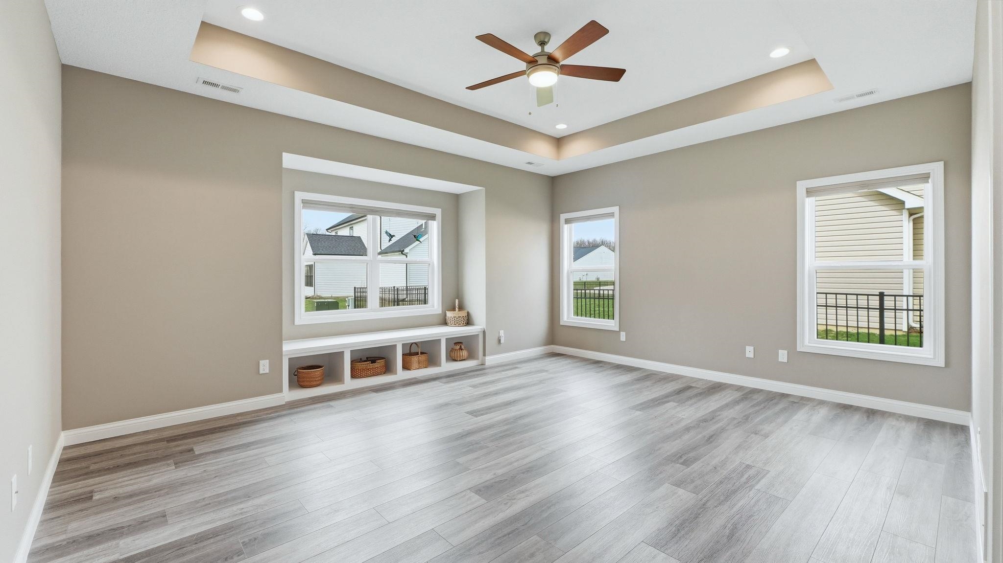 Primary Bedroom featuring ceiling fan, a raised ceiling, light wood-style floors, and recessed lighting
