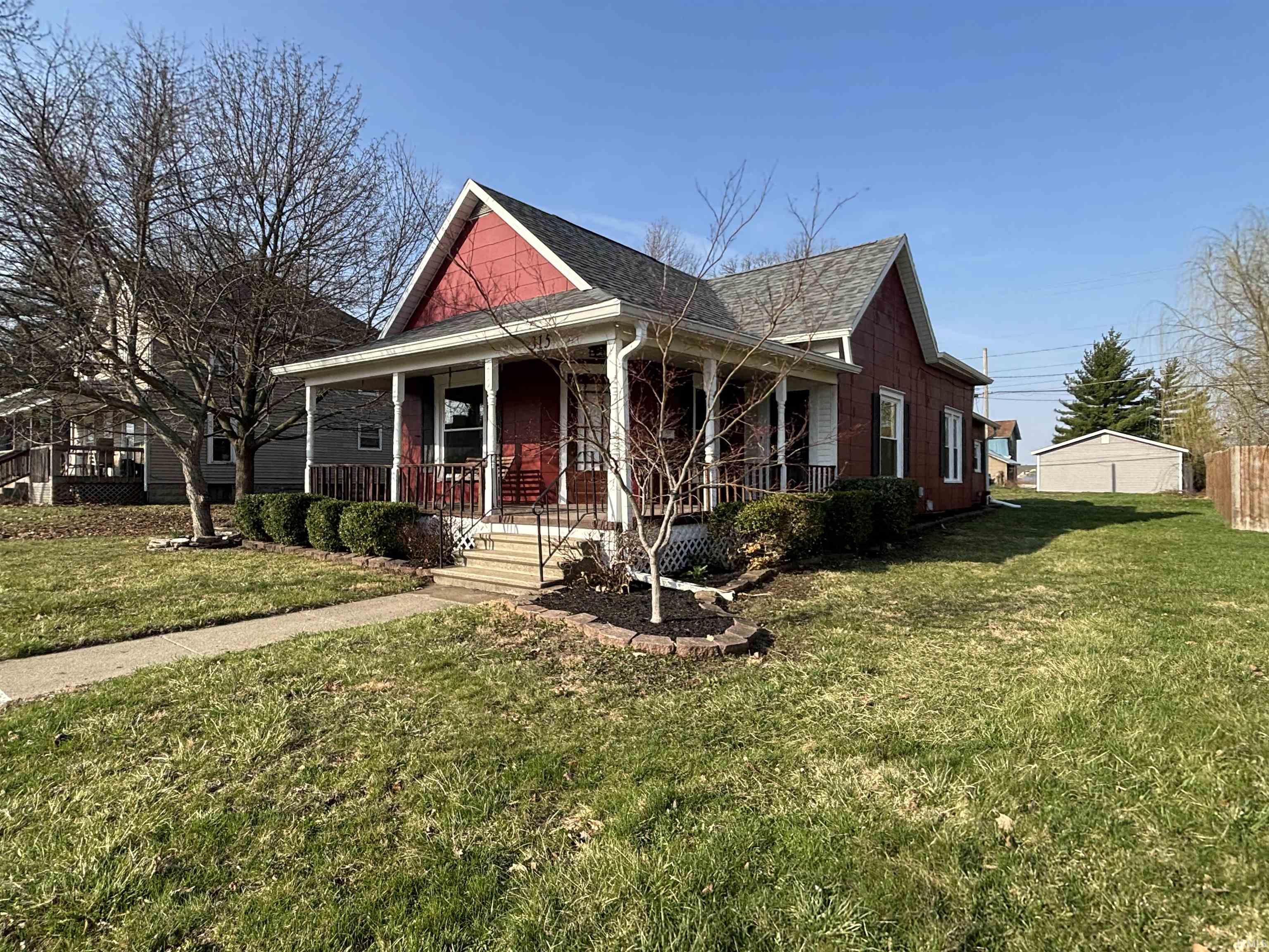 Bungalow featuring a porch, a front lawn, and a shingled roof
