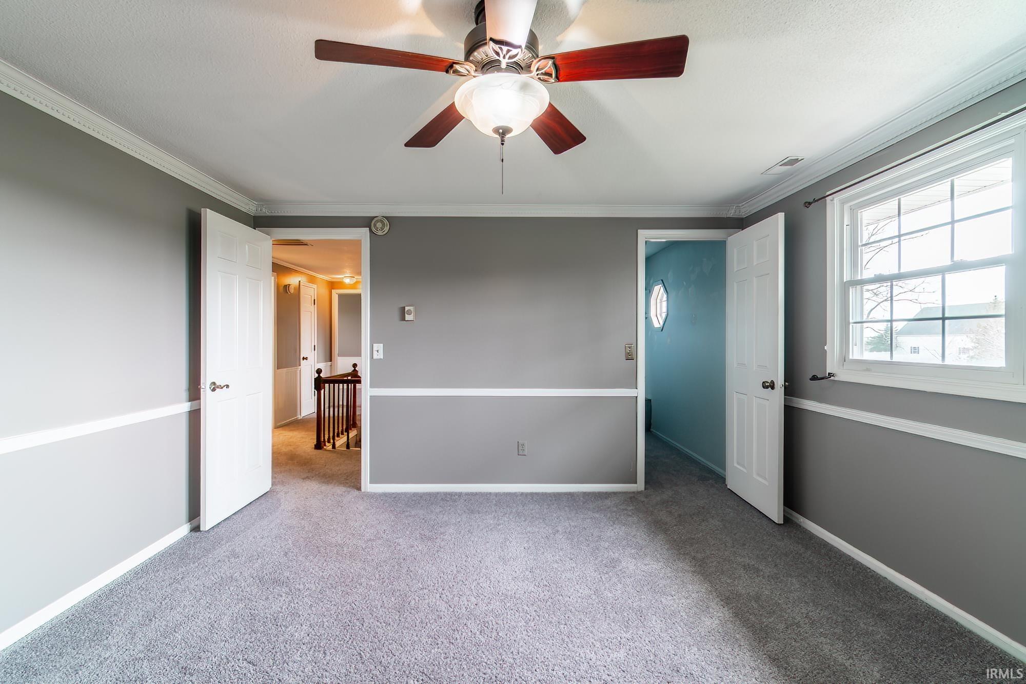 Unfurnished bedroom featuring crown molding, carpet flooring, and a ceiling fan
