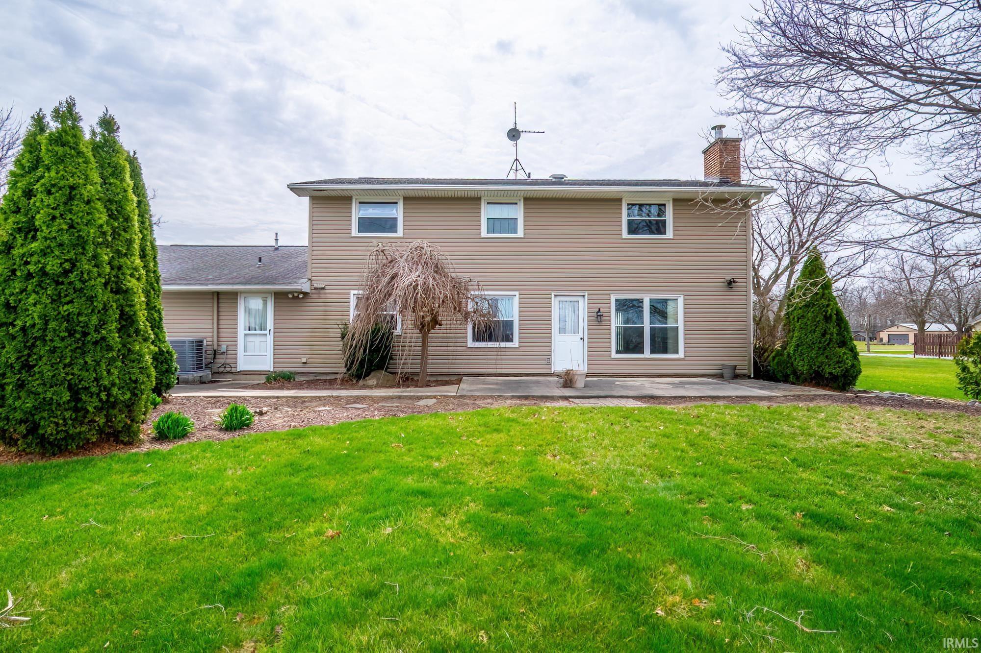 Rear view of property with a patio, a lawn, and a chimney