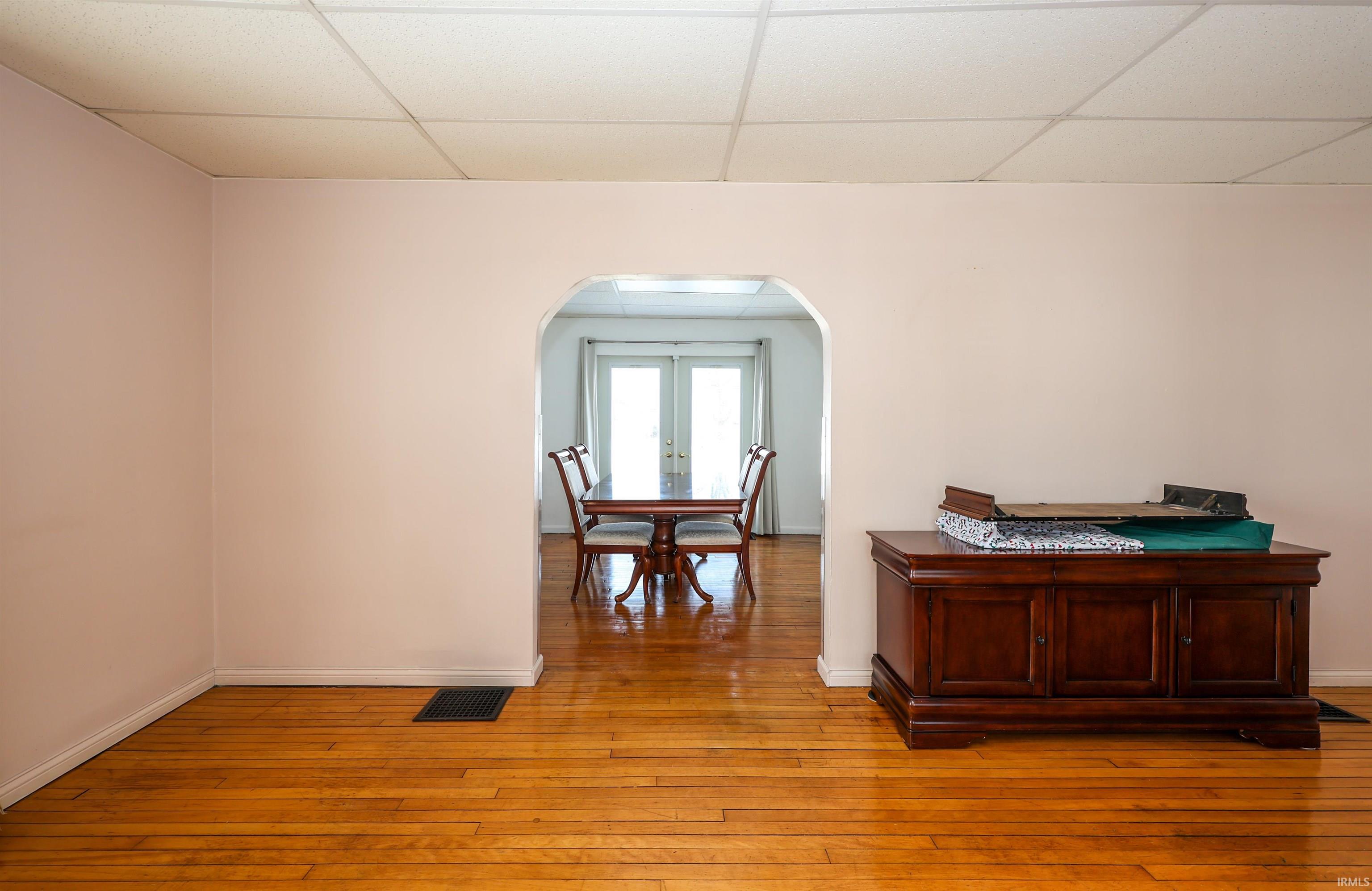 Hall featuring arched walkways, hardwood / wood-style floors, a paneled ceiling, and french doors