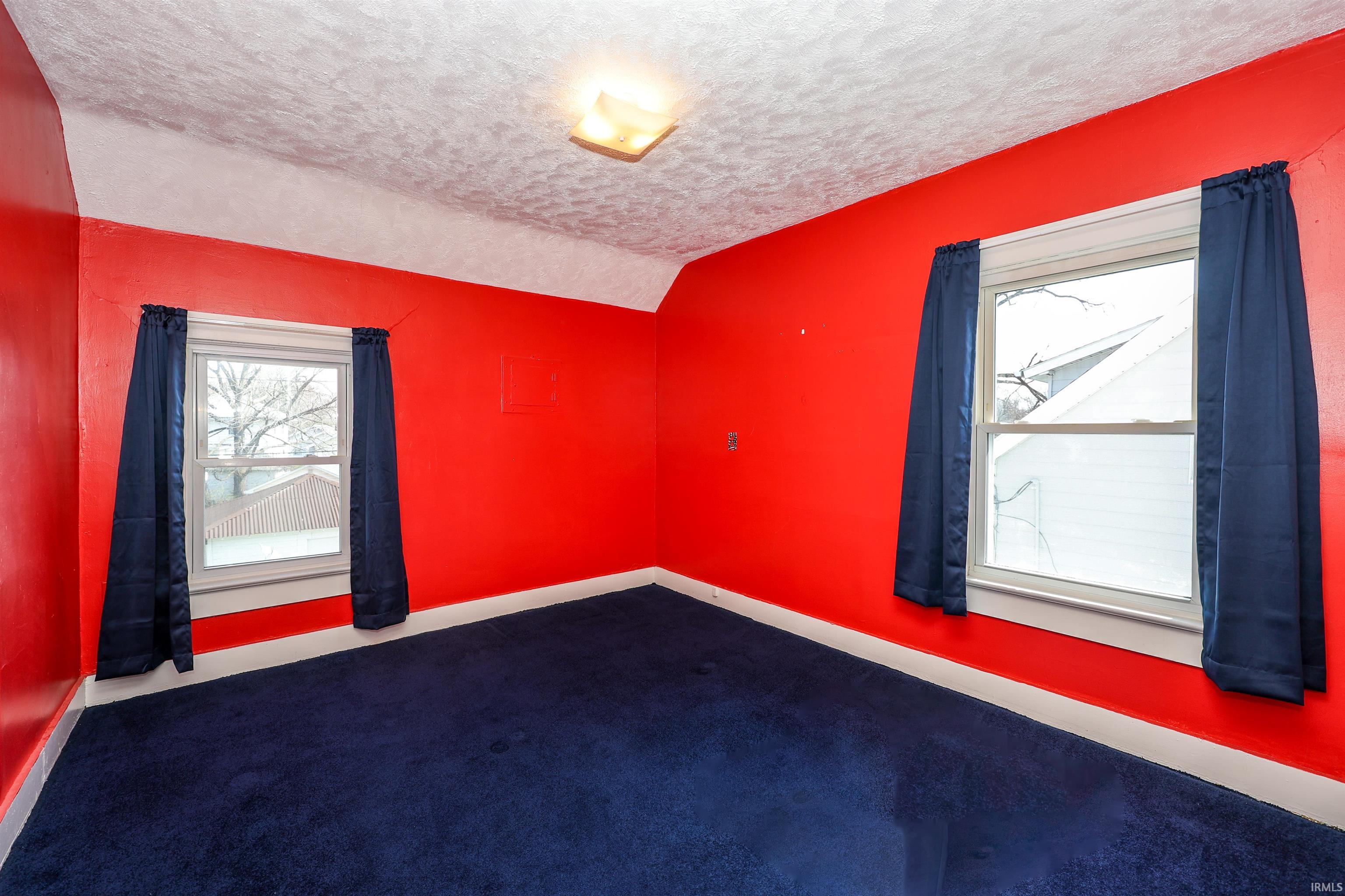 Empty room featuring dark carpet and baseboards