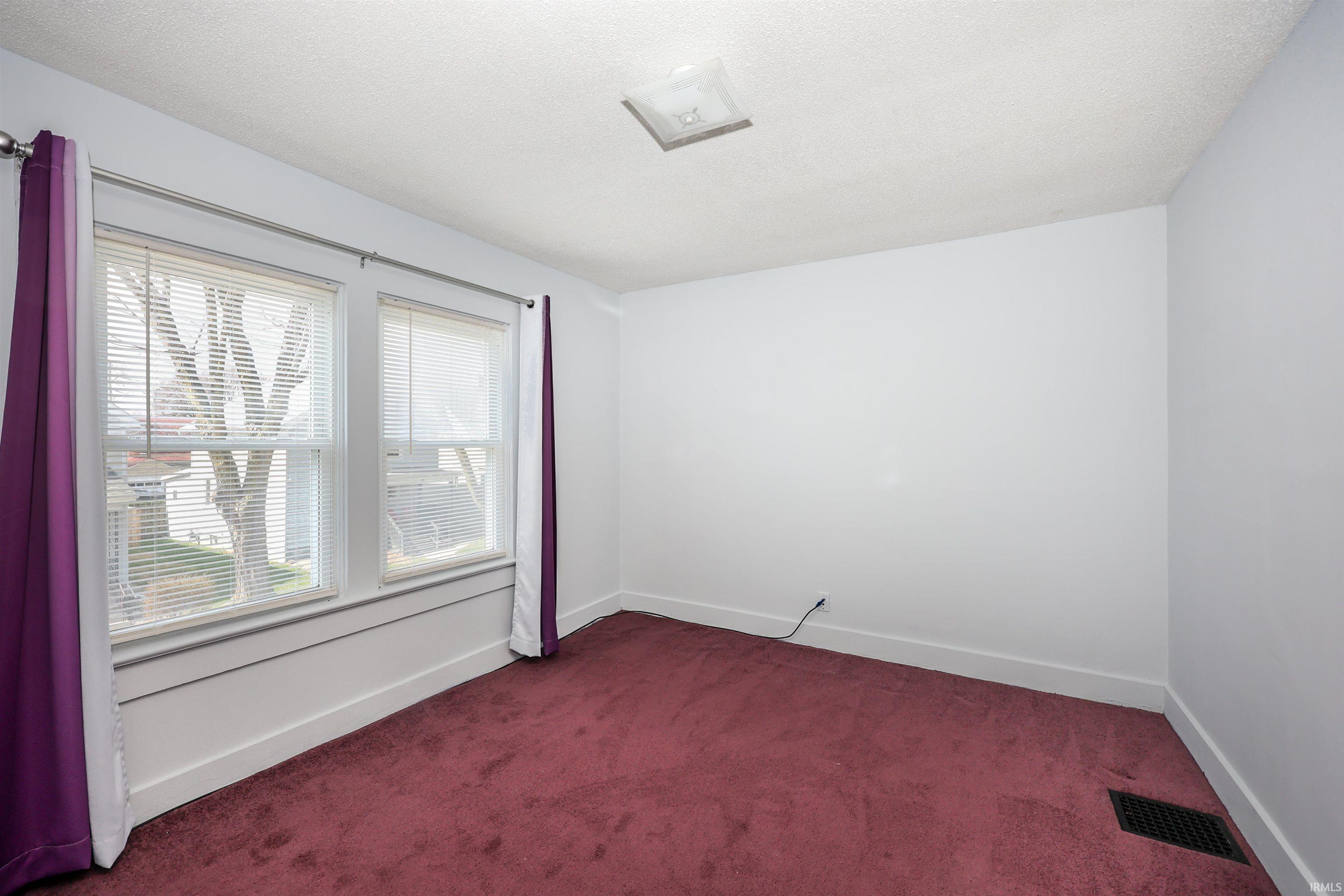Spare room with dark colored carpet and a textured ceiling