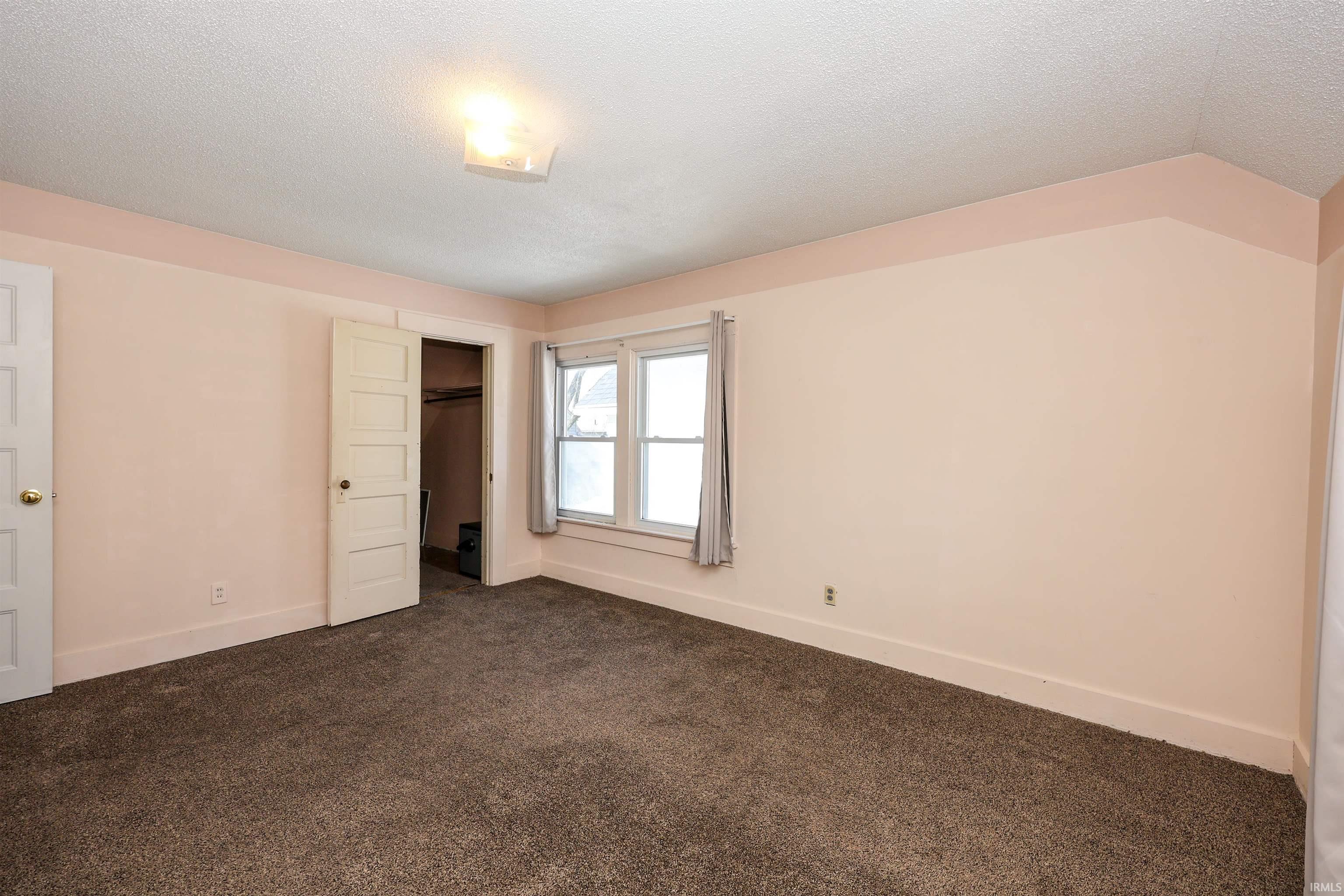 Unfurnished bedroom with carpet, a textured ceiling, and a closet