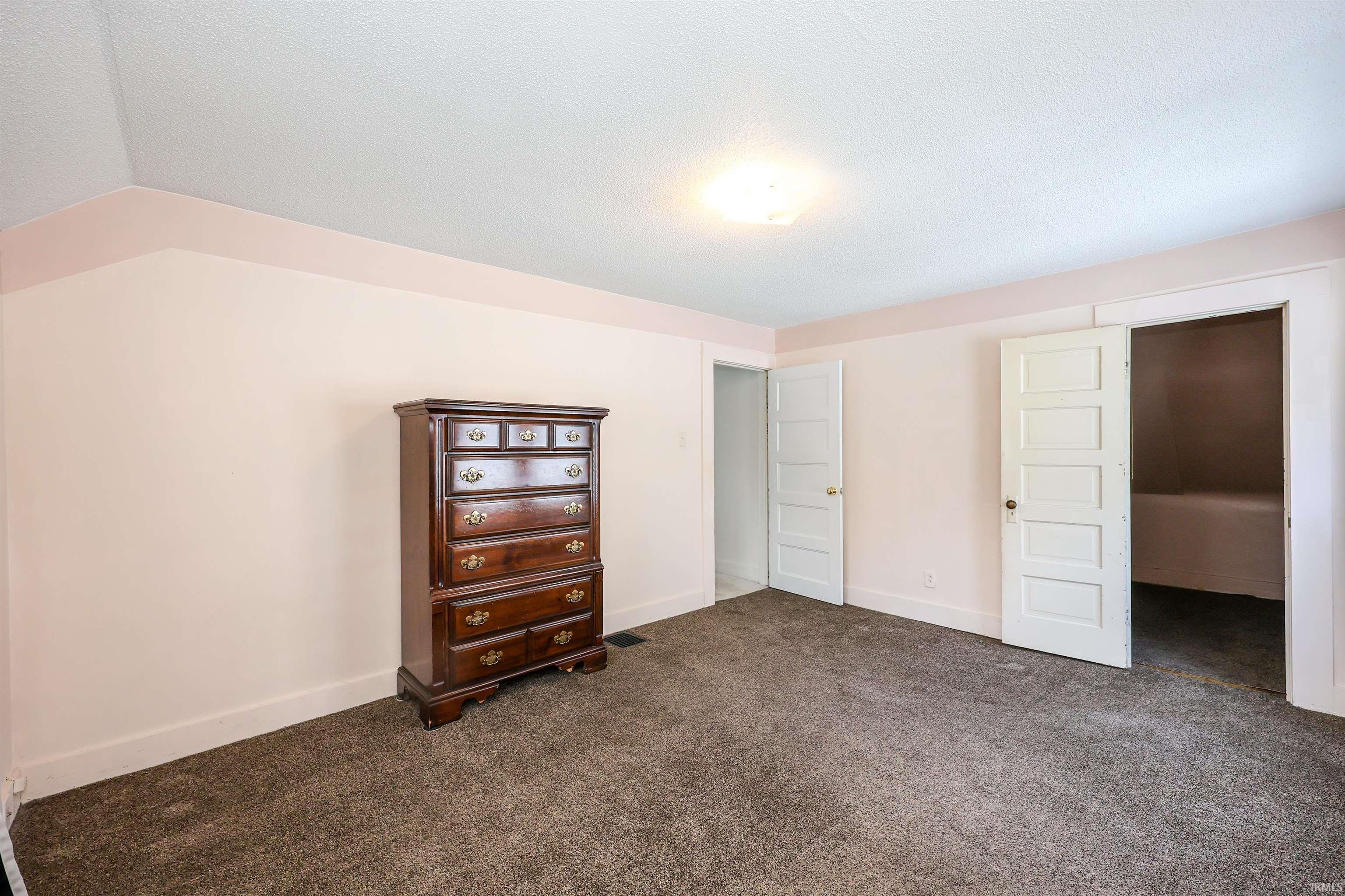 Unfurnished bedroom with dark colored carpet and a textured ceiling