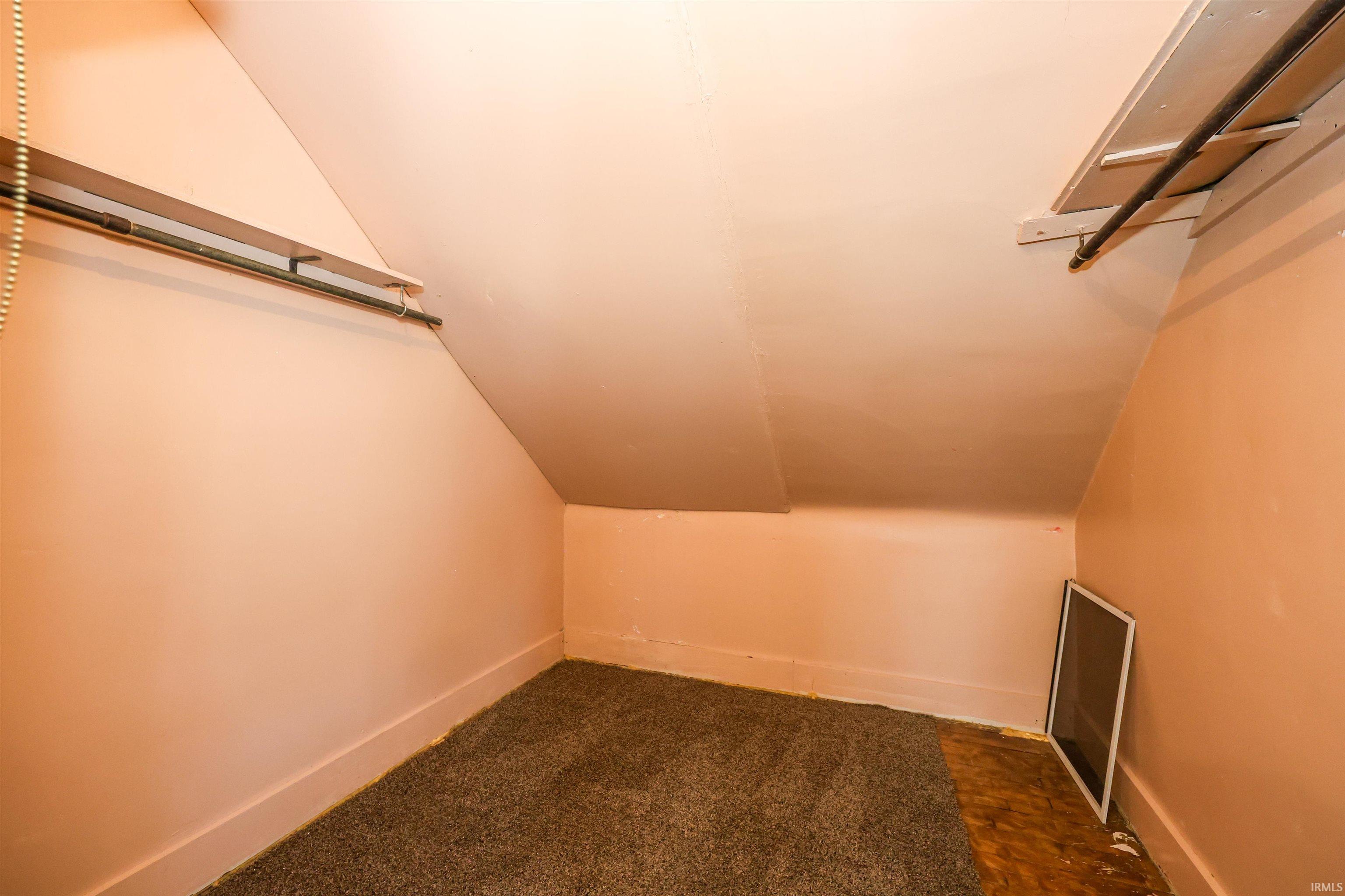Additional living space featuring lofted ceiling and dark carpet