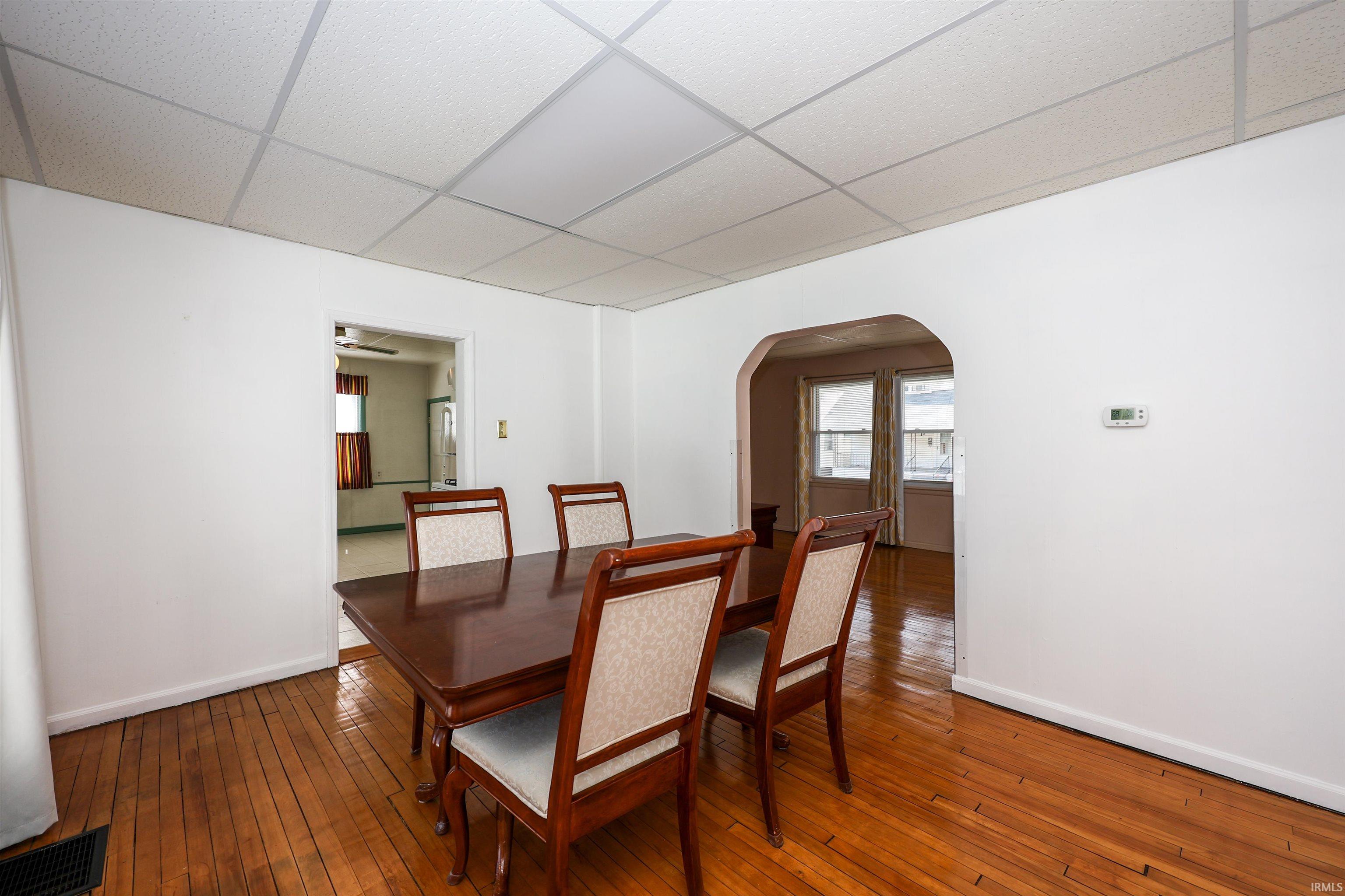 Dining area with a paneled ceiling, hardwood / wood-style flooring, arched walkways, and ceiling fan