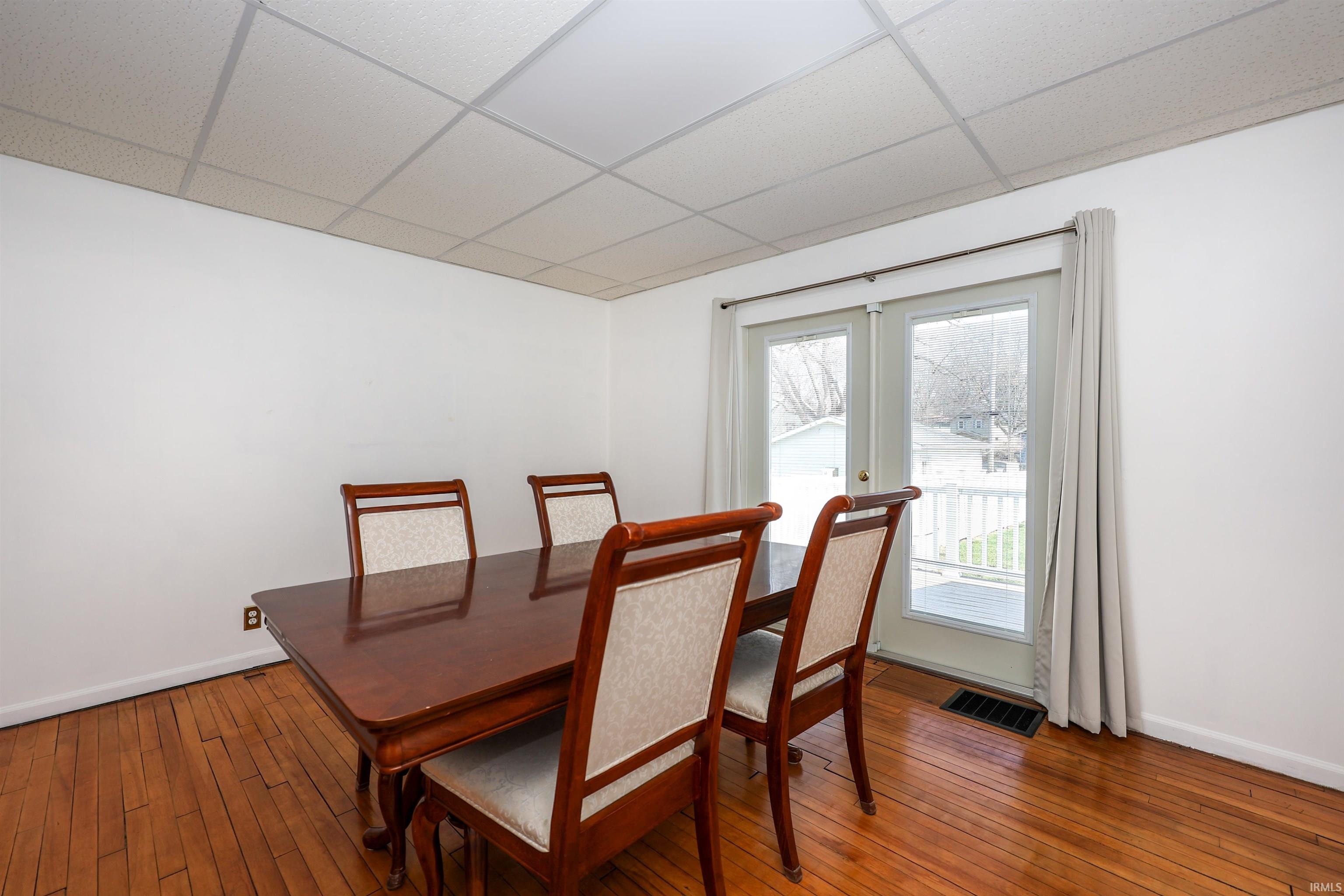 Dining area with a paneled ceiling and hardwood / wood-style flooring