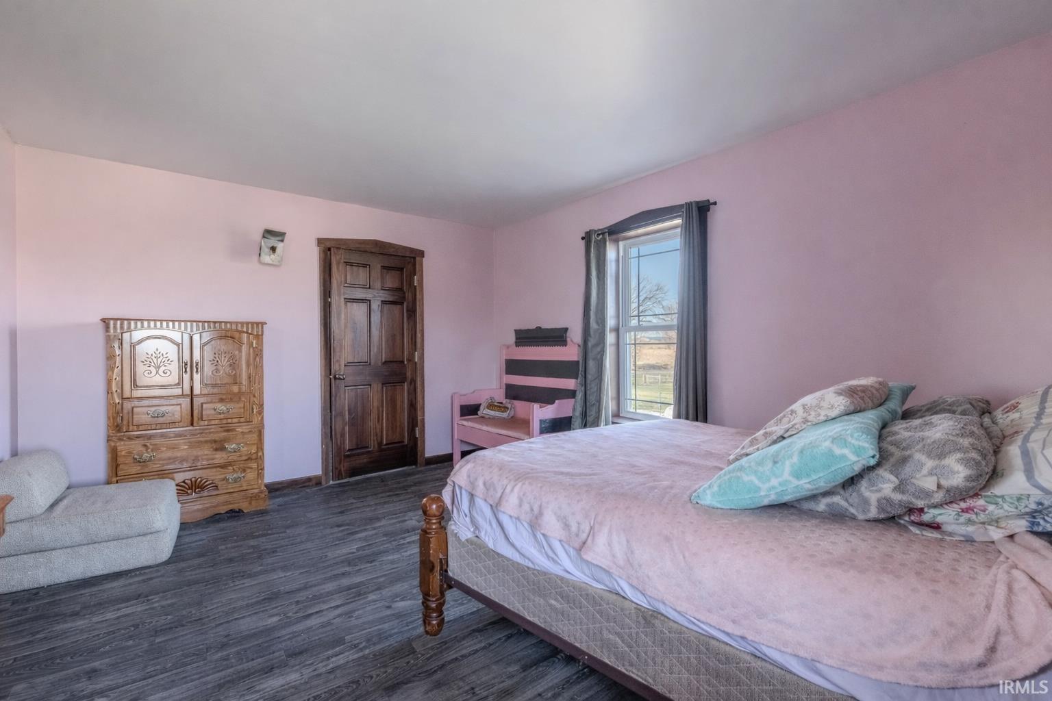 Bedroom with dark wood-type flooring and baseboards