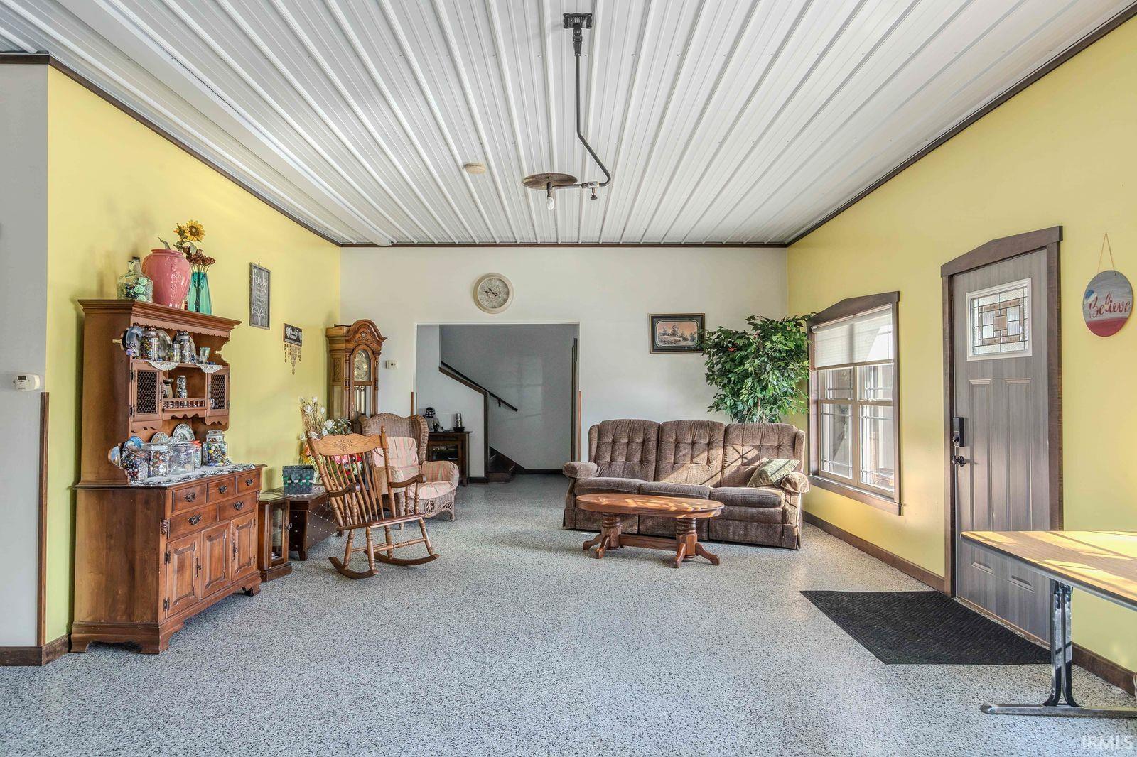 Living room featuring dark aggregate flooring and baseboards