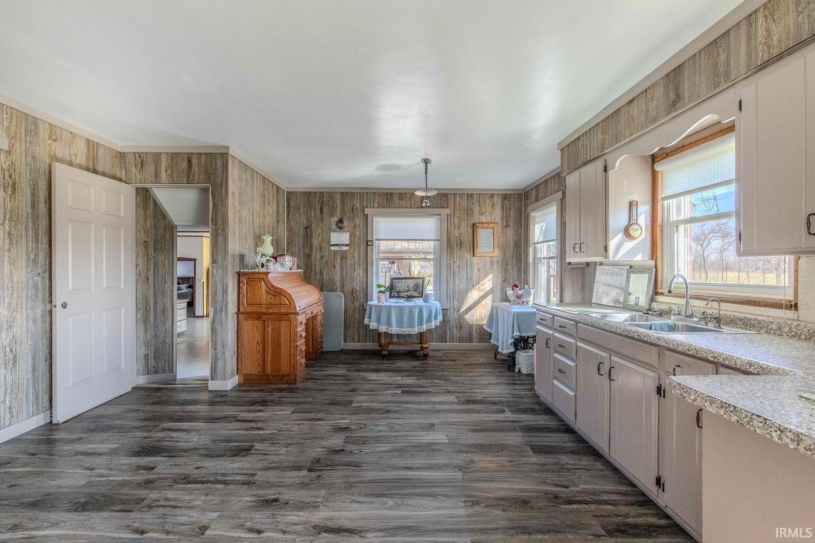 Kitchen with light countertops, dark wood finished floors, and wood walls