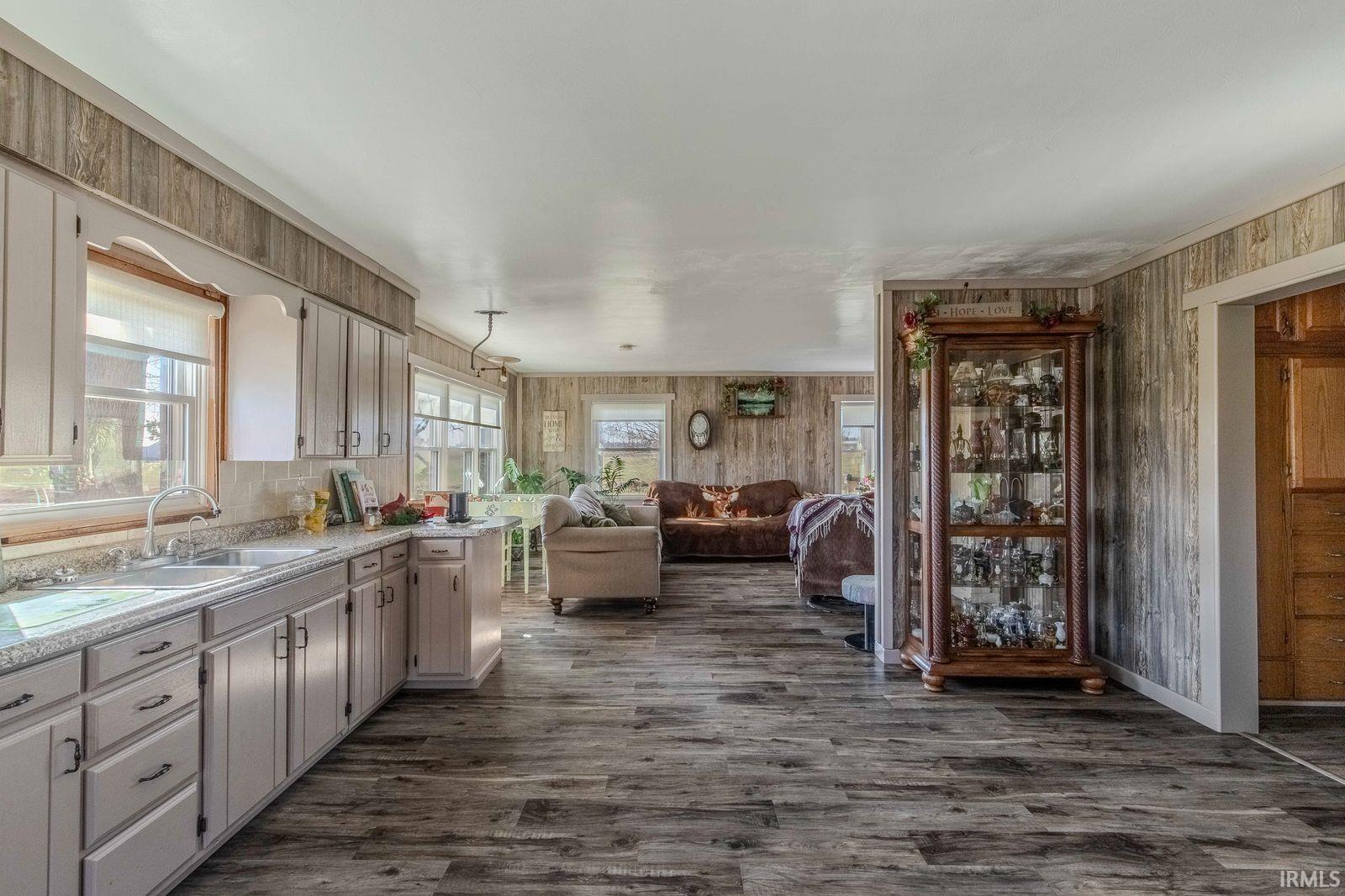 Kitchen with open floor plan, dark wood finished floors, and wood walls