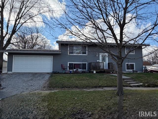 Raised ranch with driveway, a garage, and a front lawn