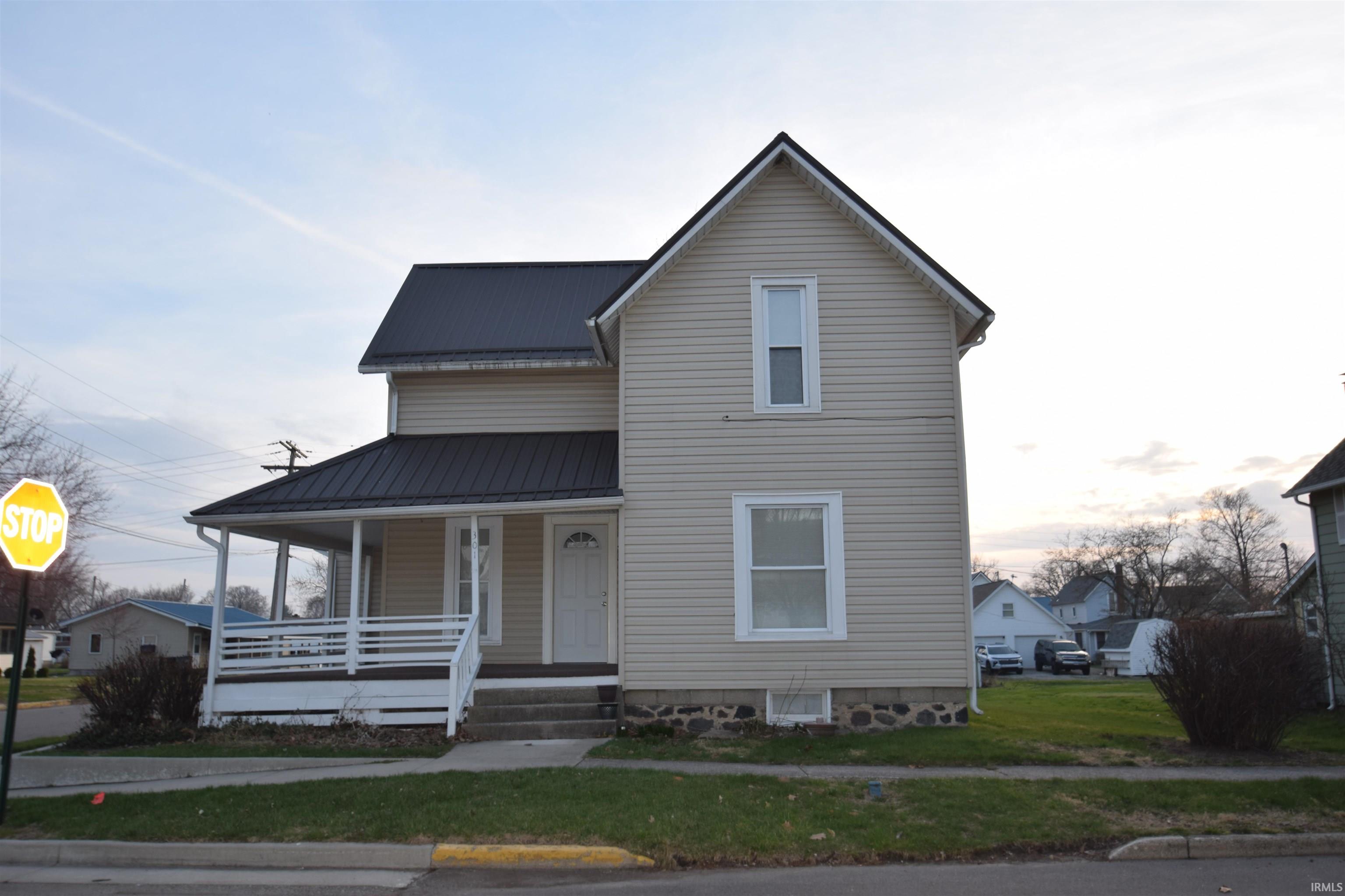 View of front of house featuring a metal roof, a porch, and a front lawn