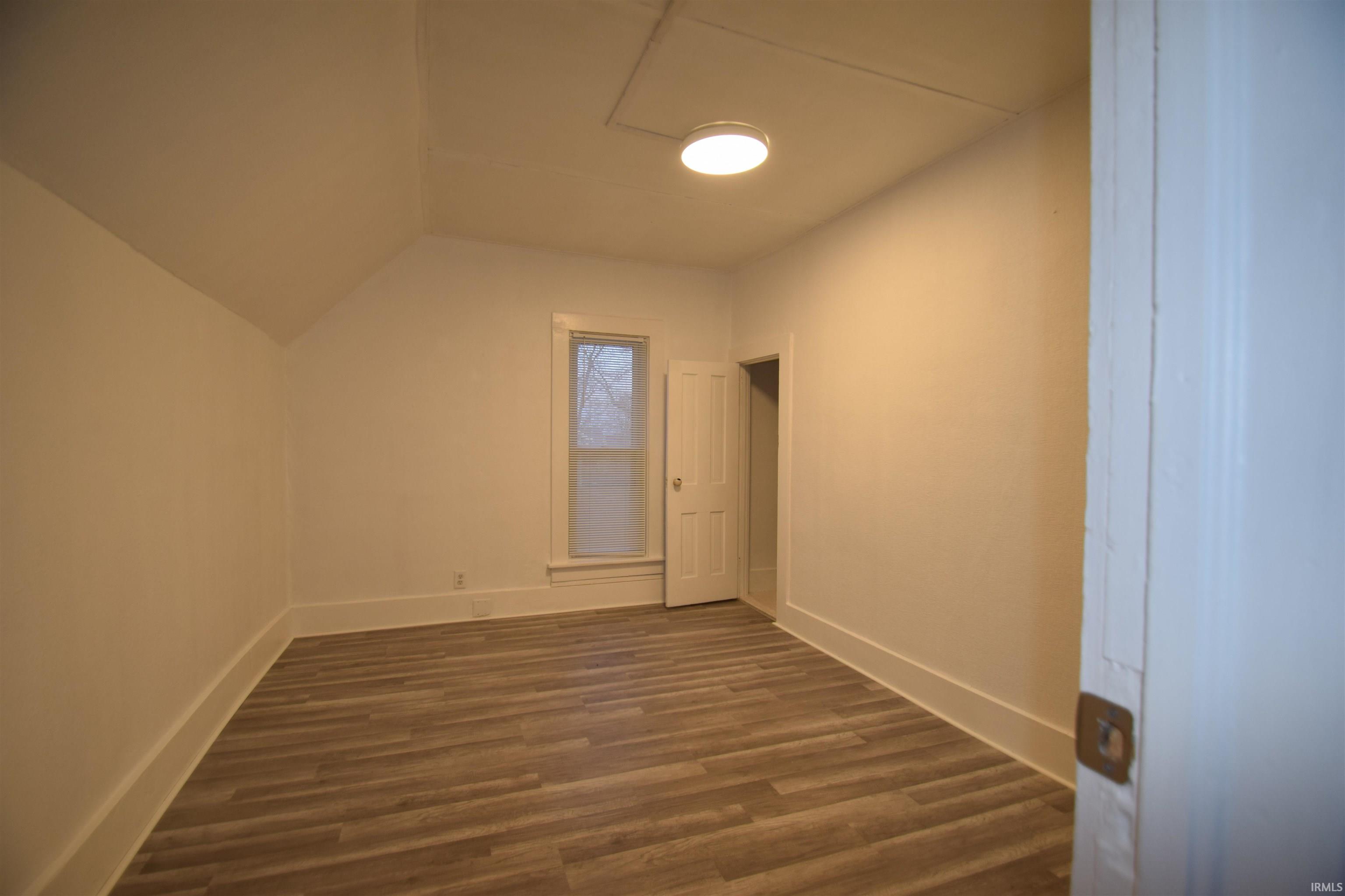 Additional living space with dark wood finished floors and vaulted ceiling