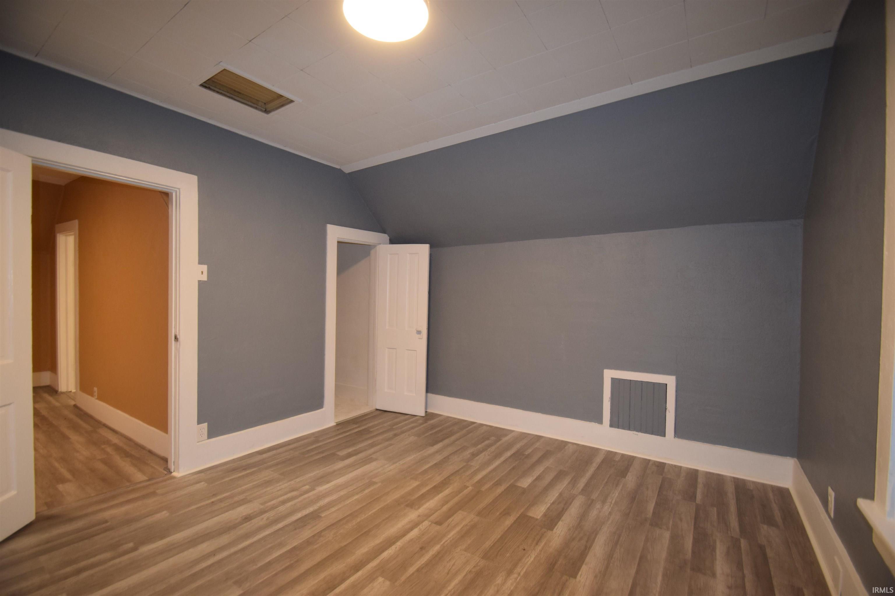 Additional living space with light wood-style flooring and lofted ceiling
