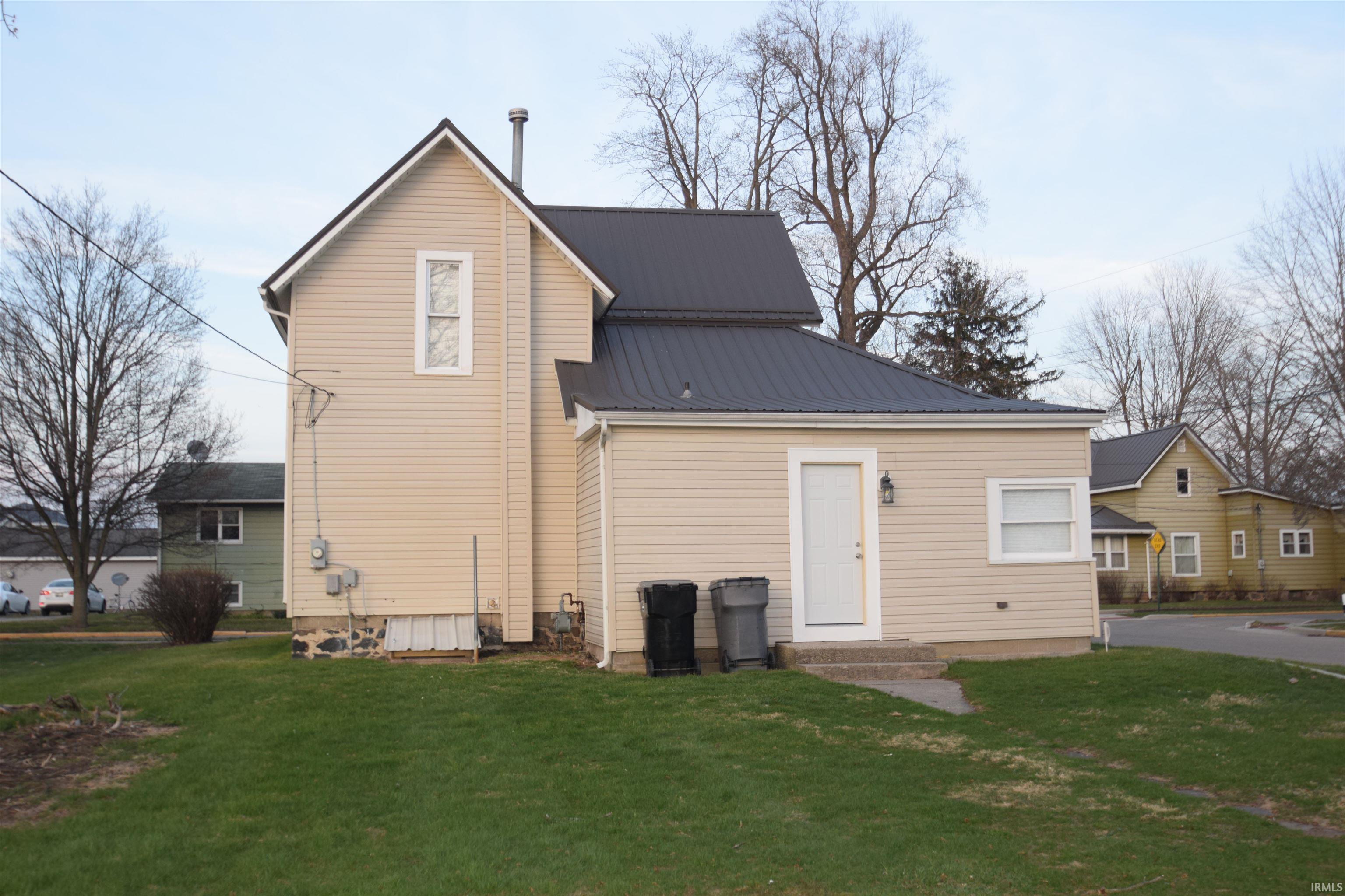 Back of house with a lawn, a metal roof, and entry steps