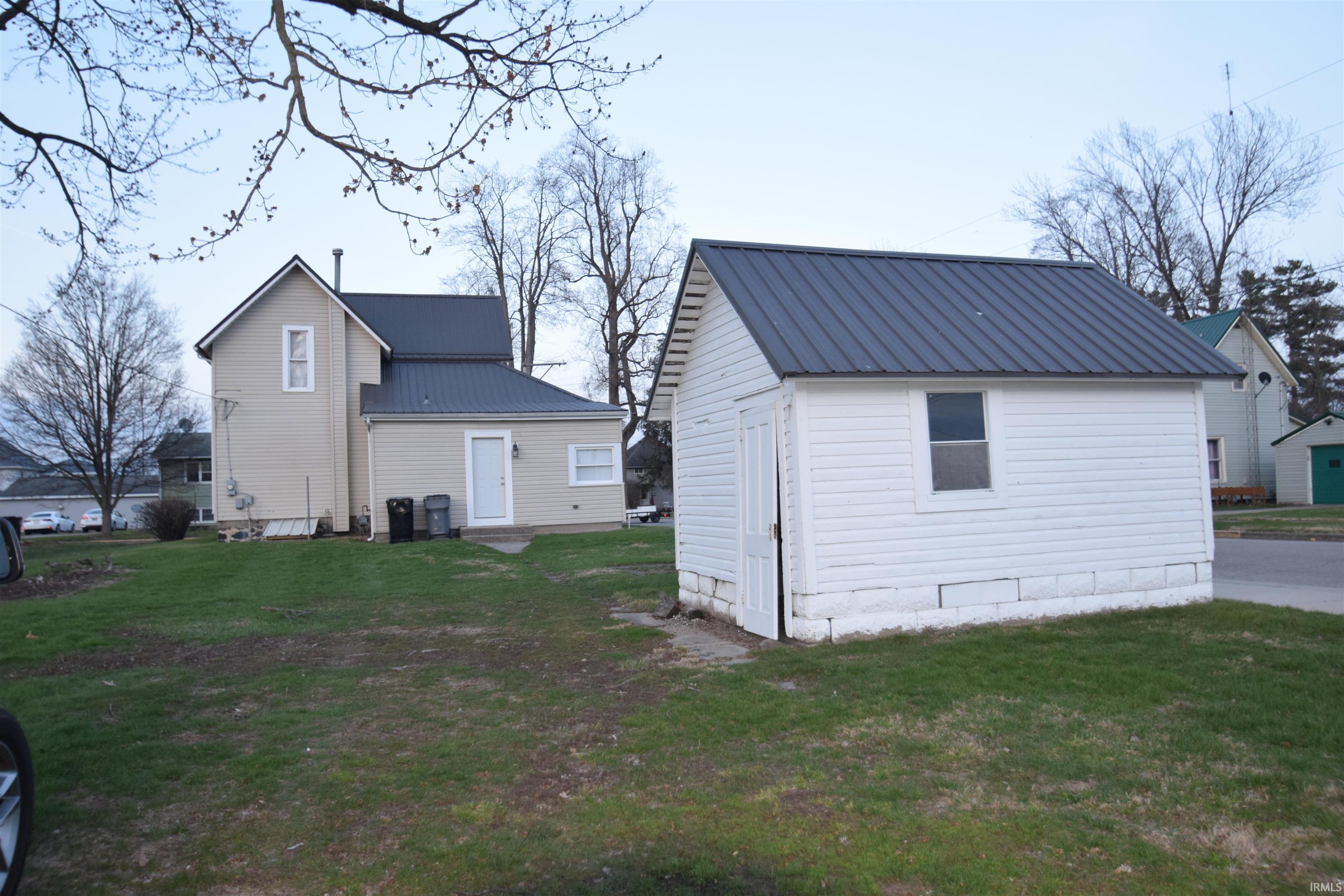 Back of property featuring a lawn and a metal roof