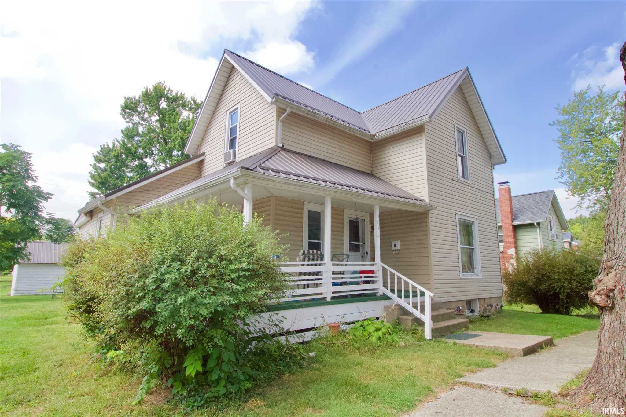 View of front of property with a front yard, a porch, and a metal roof