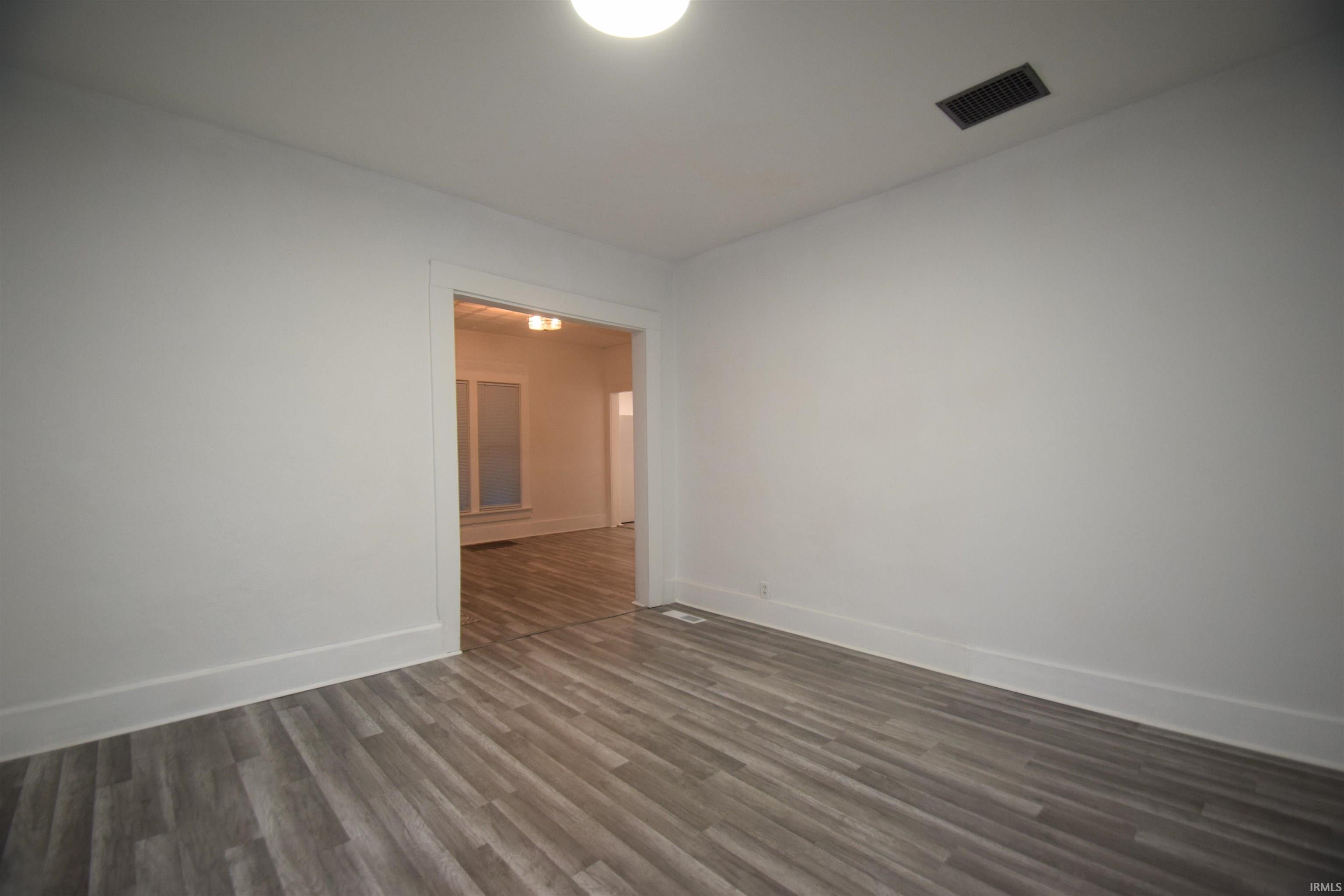 Empty room with dark wood-style flooring and baseboards