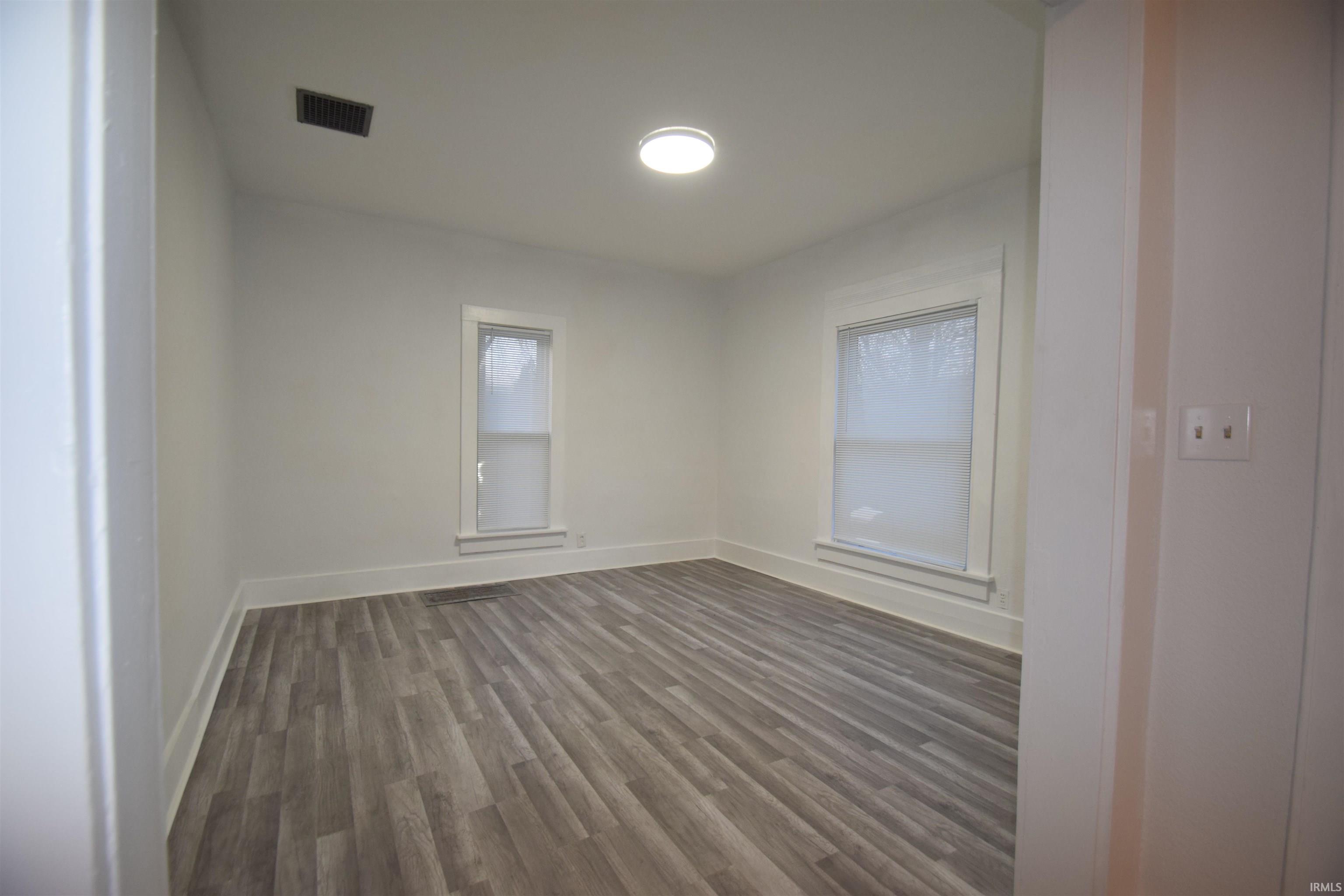 Spare room with dark wood finished floors and baseboards
